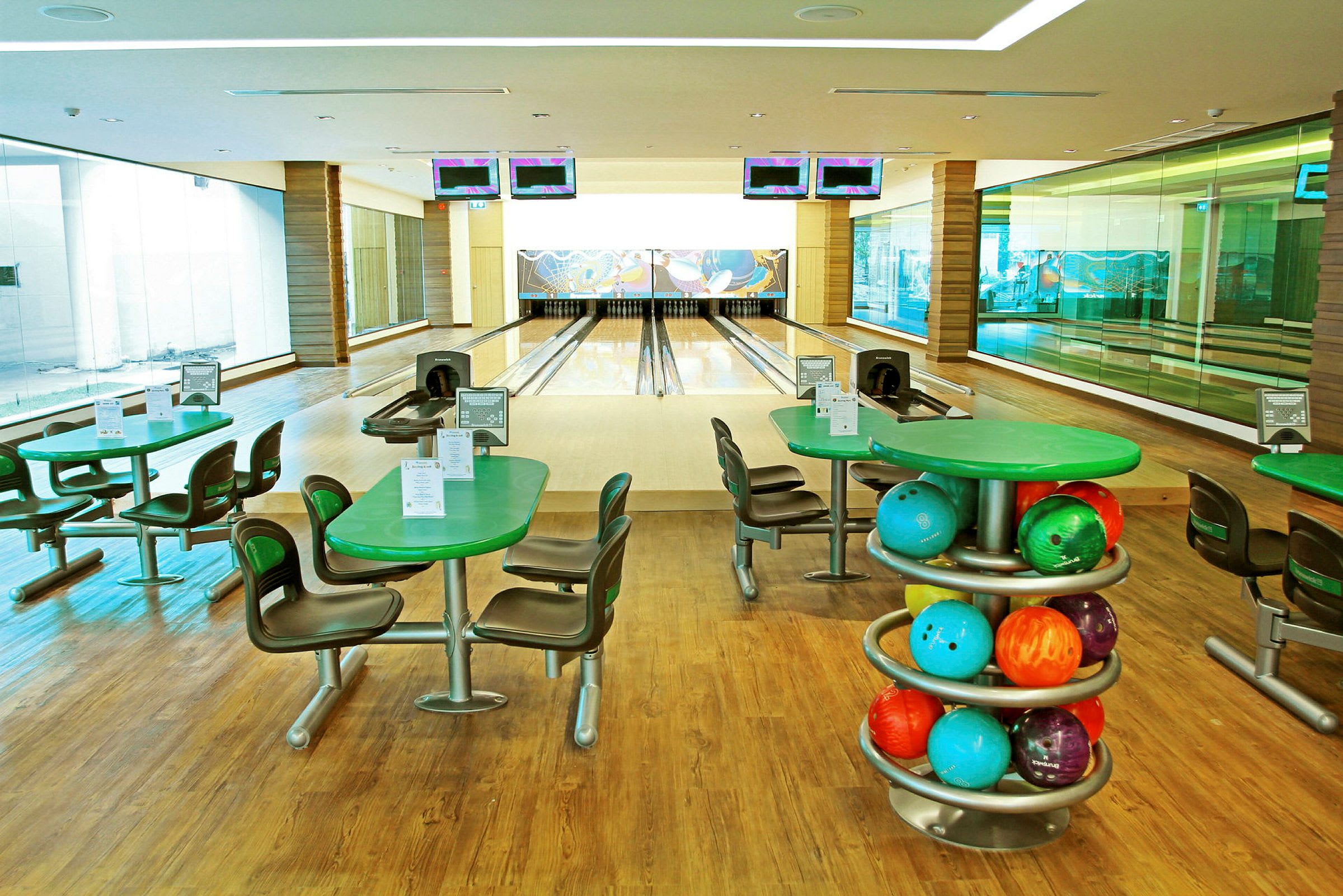 En bowlinghall med fire bowlingbaner, bord og stoler samt fargerike bowlingkuler. (AI-generert tekst)