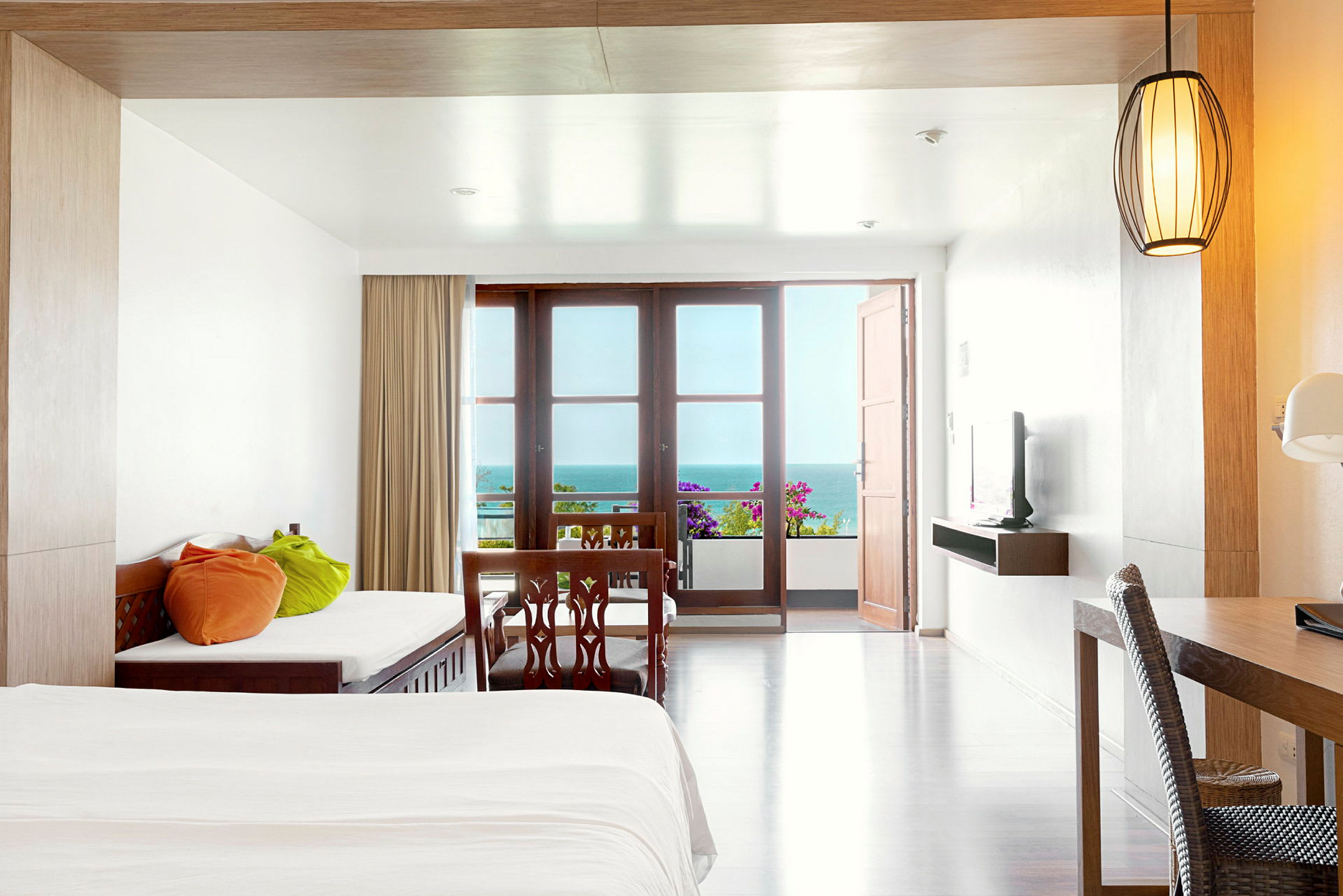 Moderne innredet hotellrom med senger, bord og utsikt over havet. (AI-generert tekst)