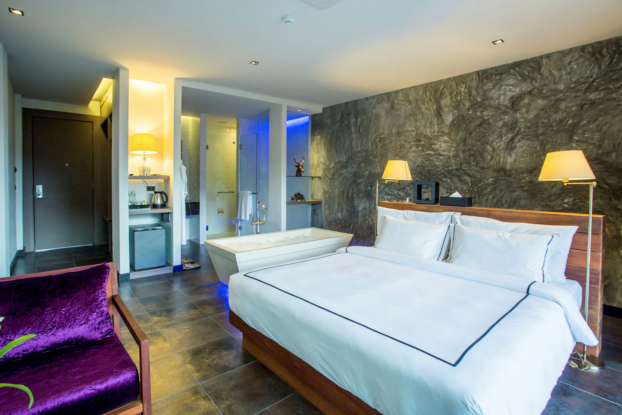 Et moderne hotellrom med en dobbeltseng, et badekar ved siden av og en elegant innredning. (AI-generert tekst)
