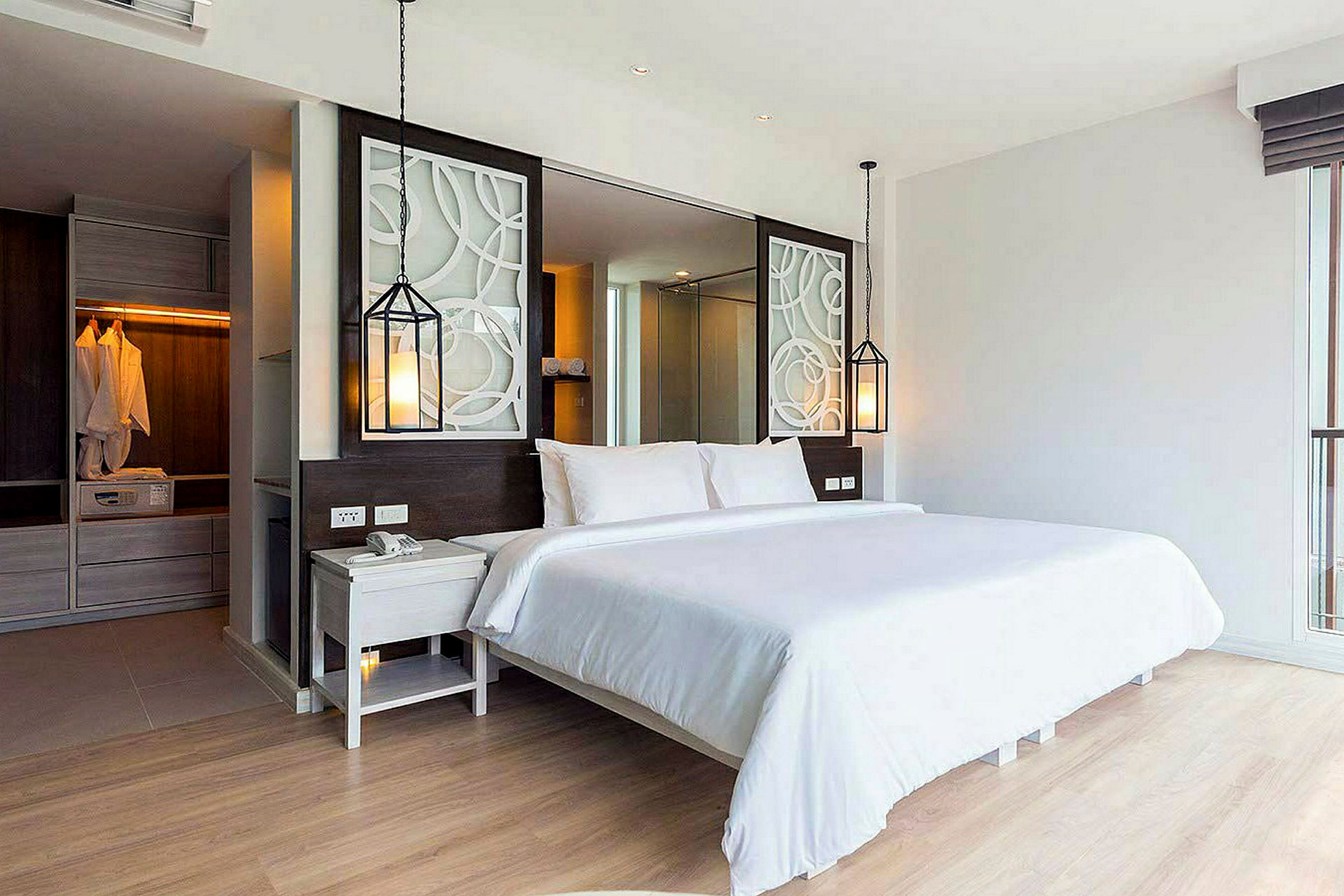 En moderne hotellsuite med en komfortabel dobbeltseng, dekorative elementer og et skap i bakgrunnen. (AI-generert tekst)