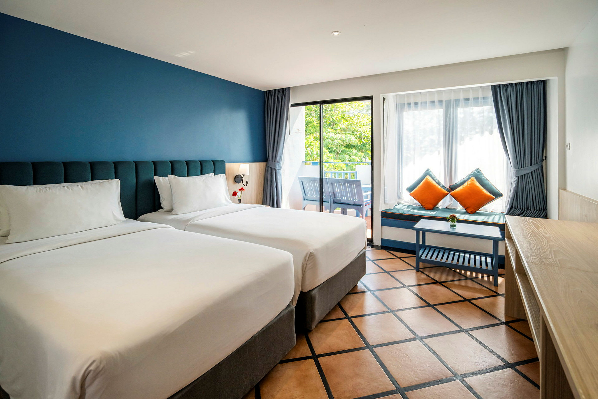 To enkeltsenger på et hotellrom med blå vegger og store vinduer. (AI-generert tekst)