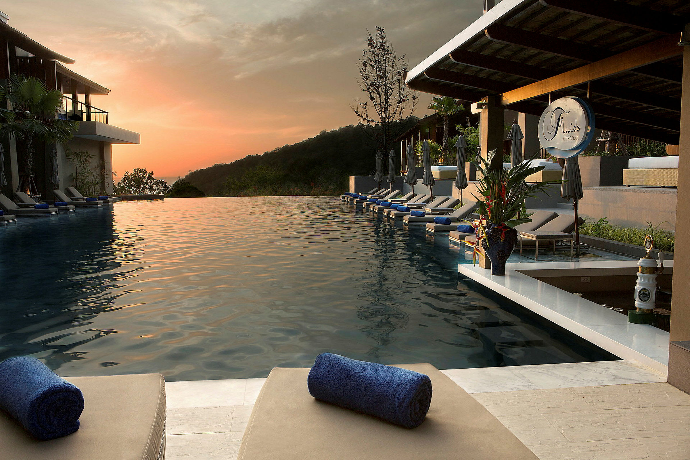 Et uendeligbasseng med solsenger og håndklær på en resort ved solnedgang. (AI-generert tekst)