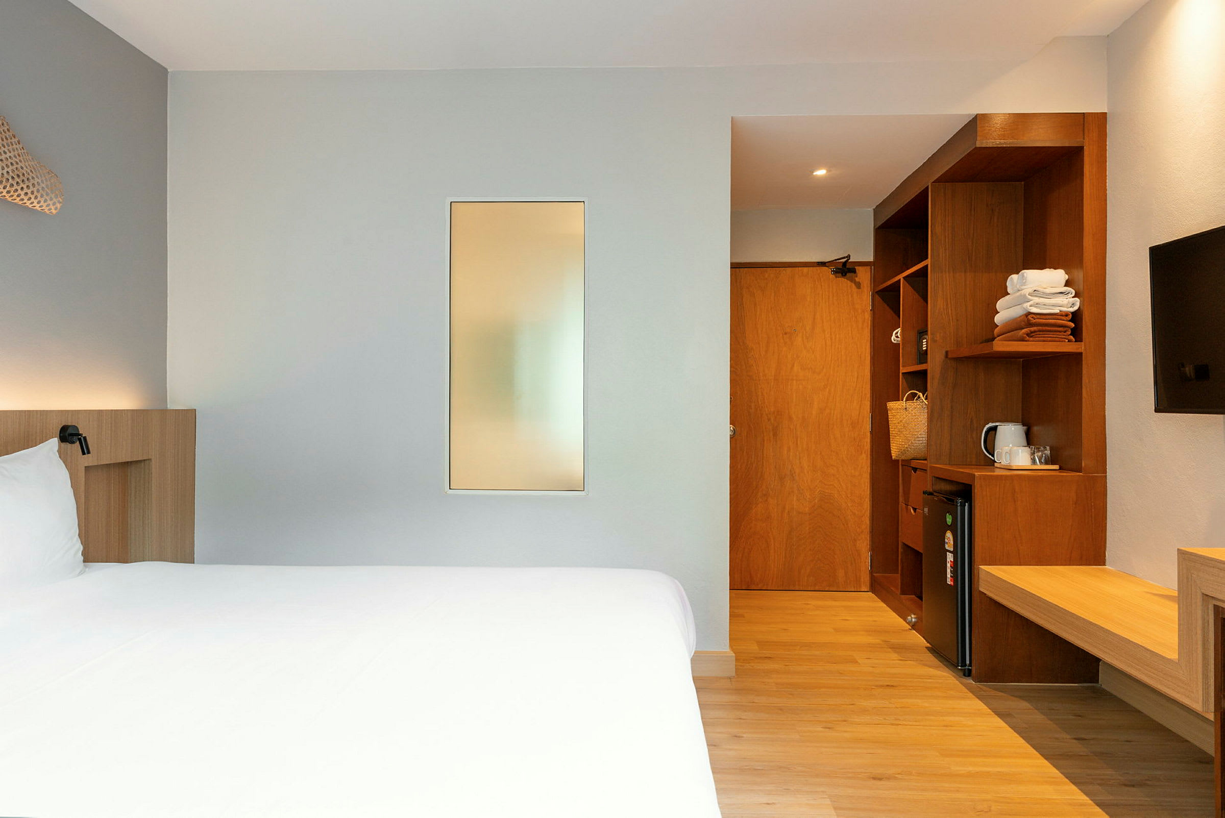 Et hotellrom med en seng, en garderobe, en minibar og en tv. (AI-generert tekst)