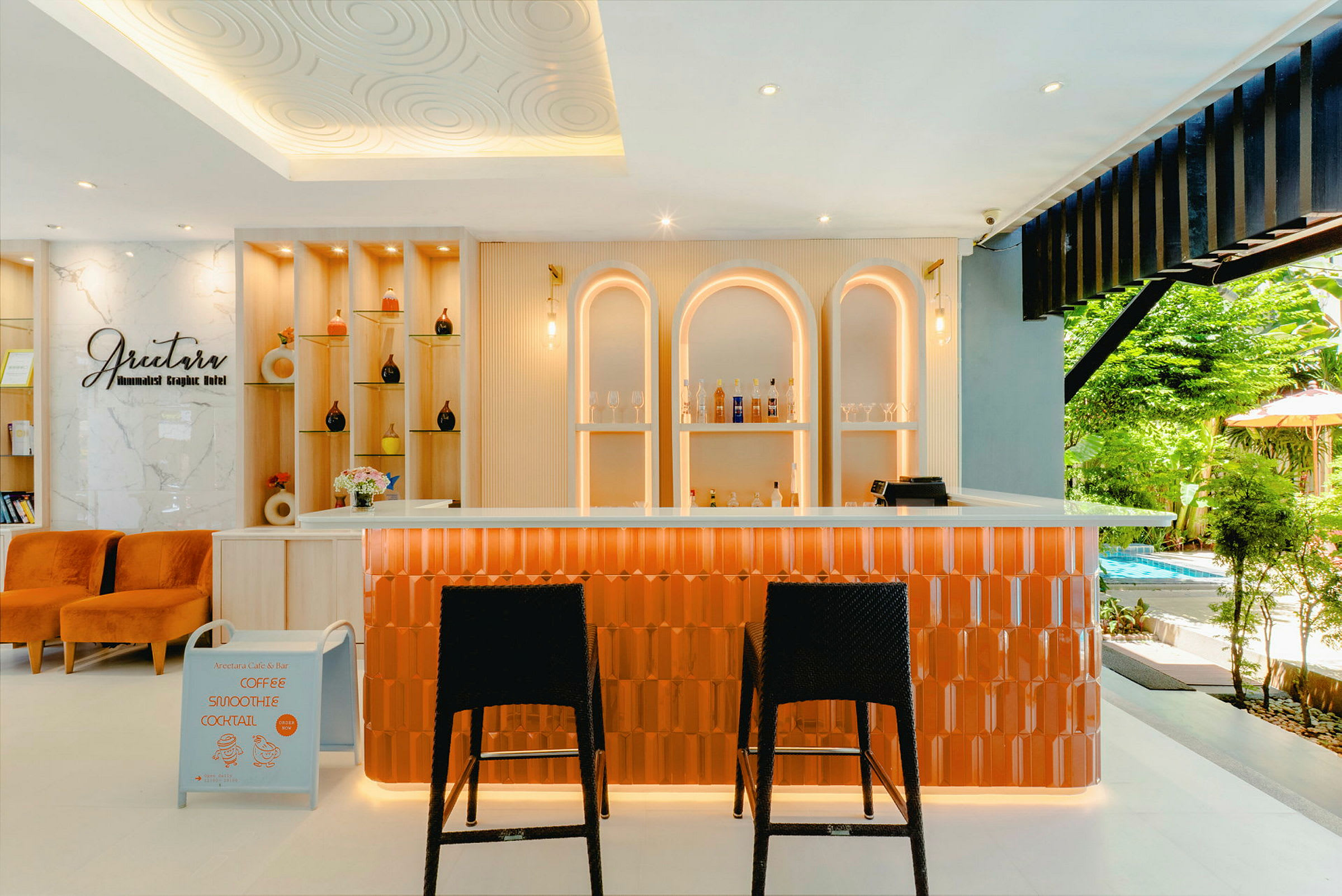 En smakfullt innredet kafé eller bar med oransje detaljer og moderne belysning. I bakgrunnen sees hyller med dekorative gjenstander og flasker. (AI-generert tekst)