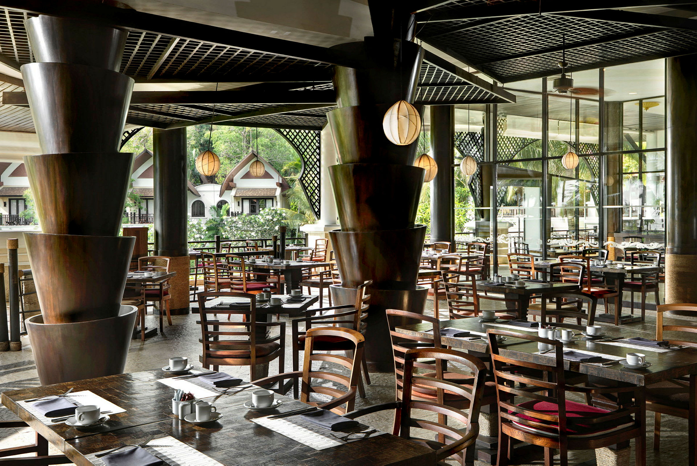 En moderne restaurant med elegante trebord og stoler, omgitt av grøntområder og store vinduer. (AI-generert tekst)