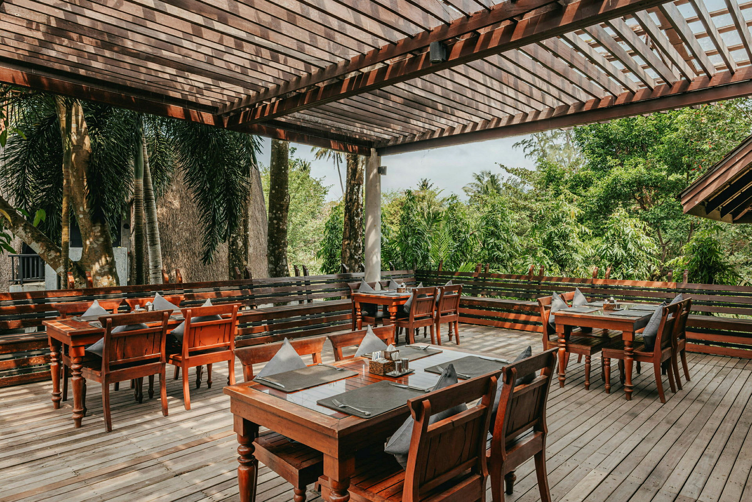 Uteservering med tremøbler og utsikt mot frodige omgivelser. (AI-generert tekst)