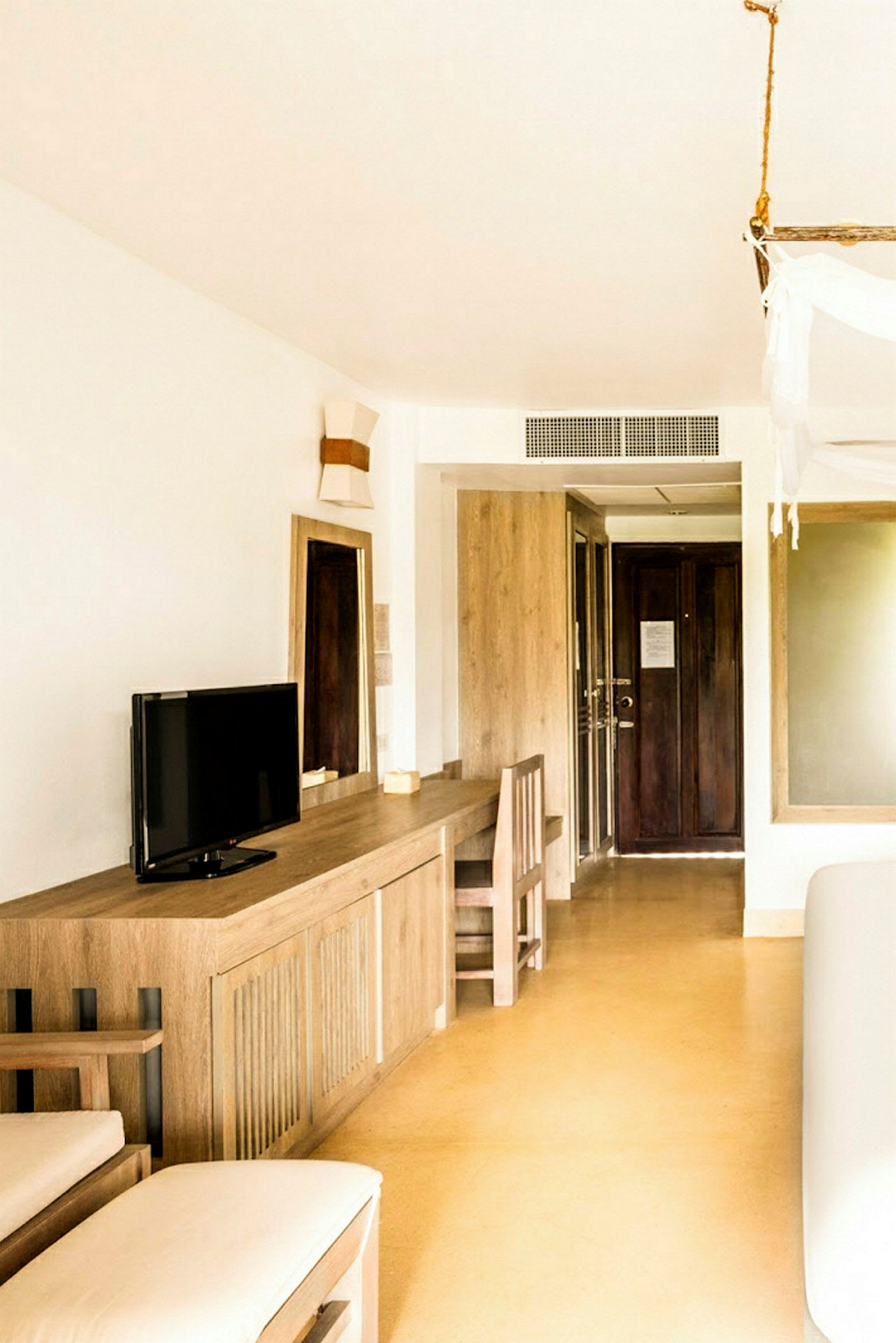 Et hotellrom med minimalistisk innredning, inkludert et skrivebord, en stol og en liten TV. (AI-generert tekst)