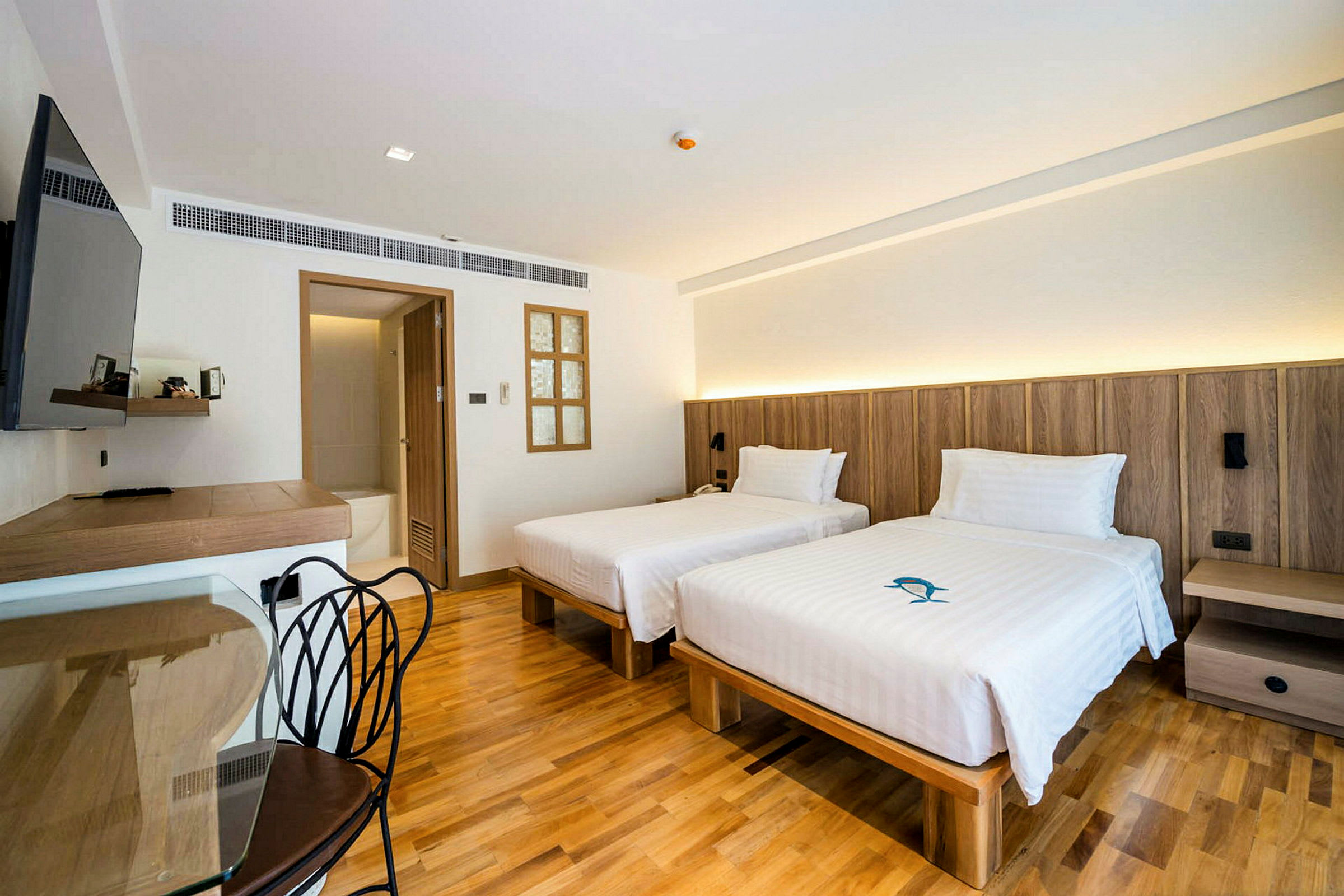 Hotellrom med to enkeltsenger, tregulv og moderne møbler. (AI-generert tekst)