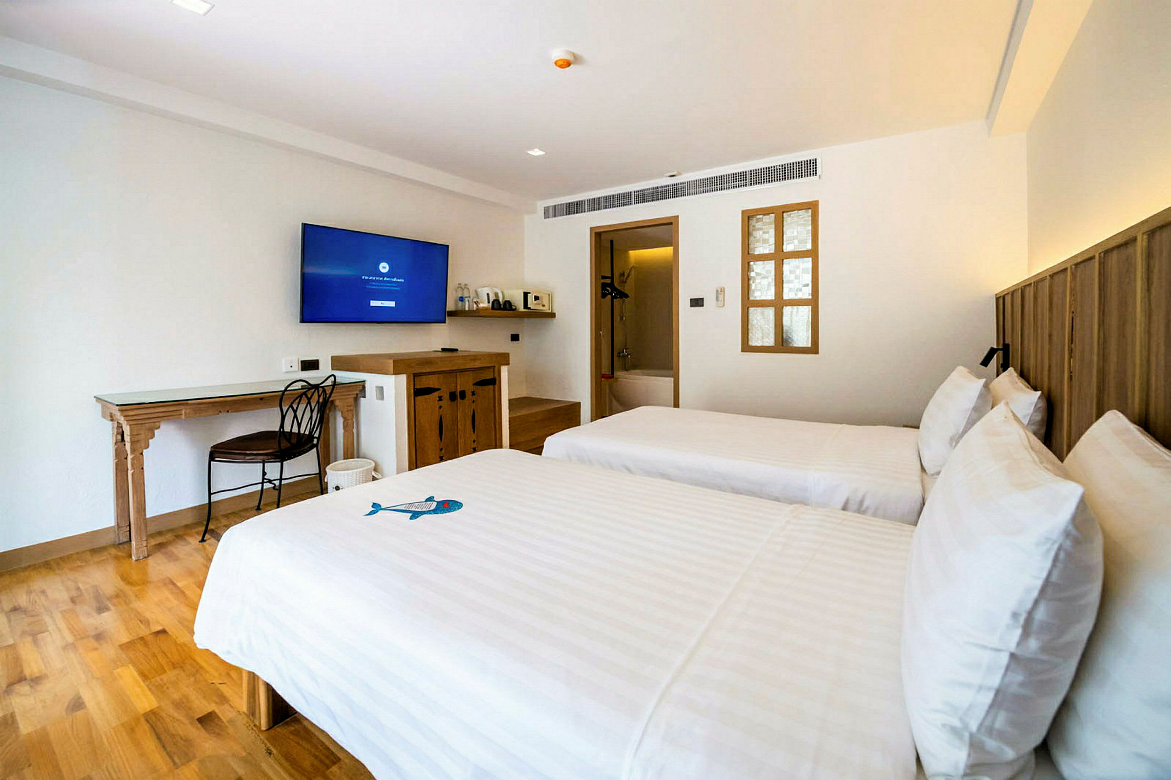 Et hotellrom med to enkeltsenger, en TV på veggen og solide tremøbler. (AI-generert tekst)