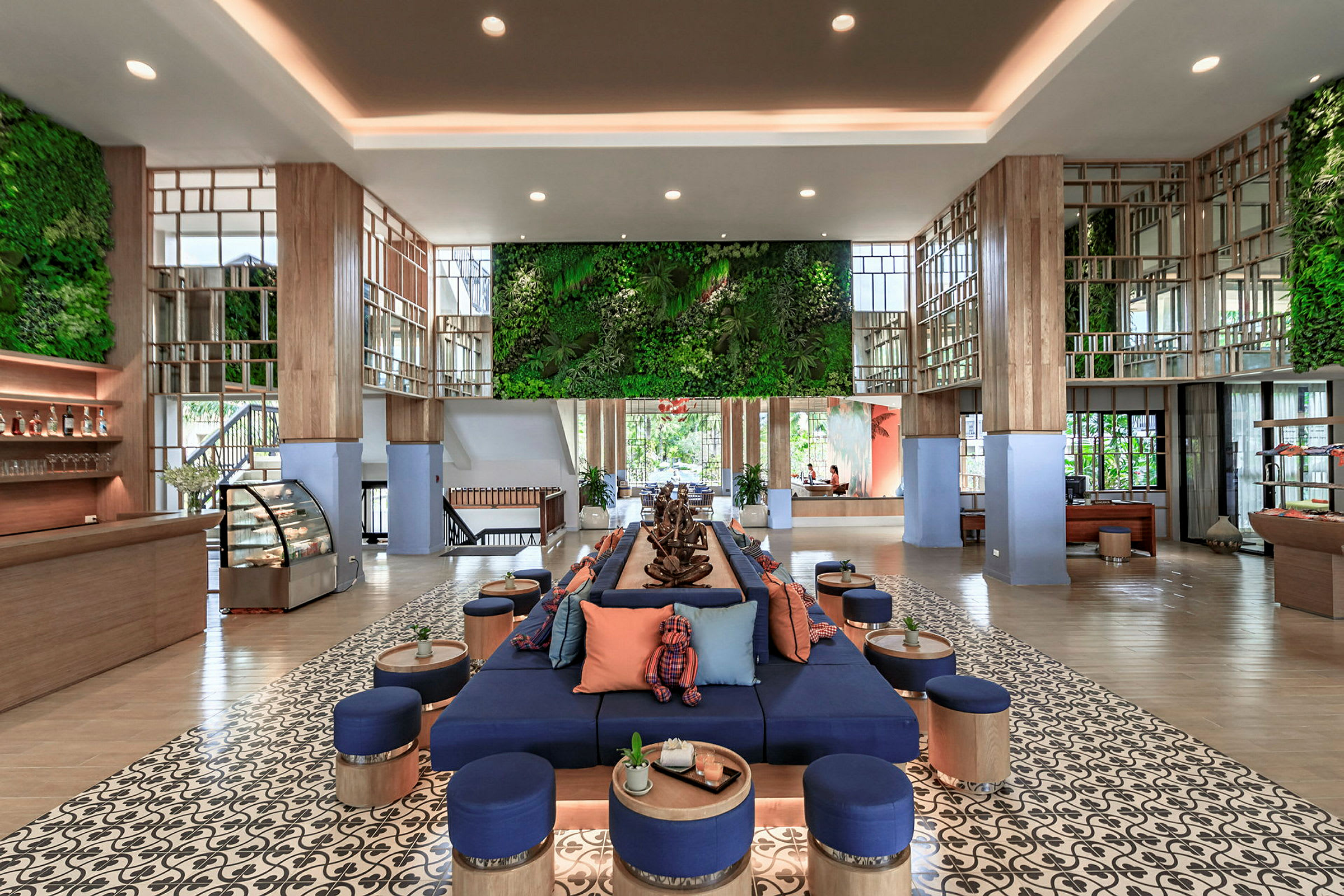 Et moderne hotellobbyområde med en sentral sittegruppe, grønne veggpaneler og dekorative tredetaljer. (AI-generert tekst)