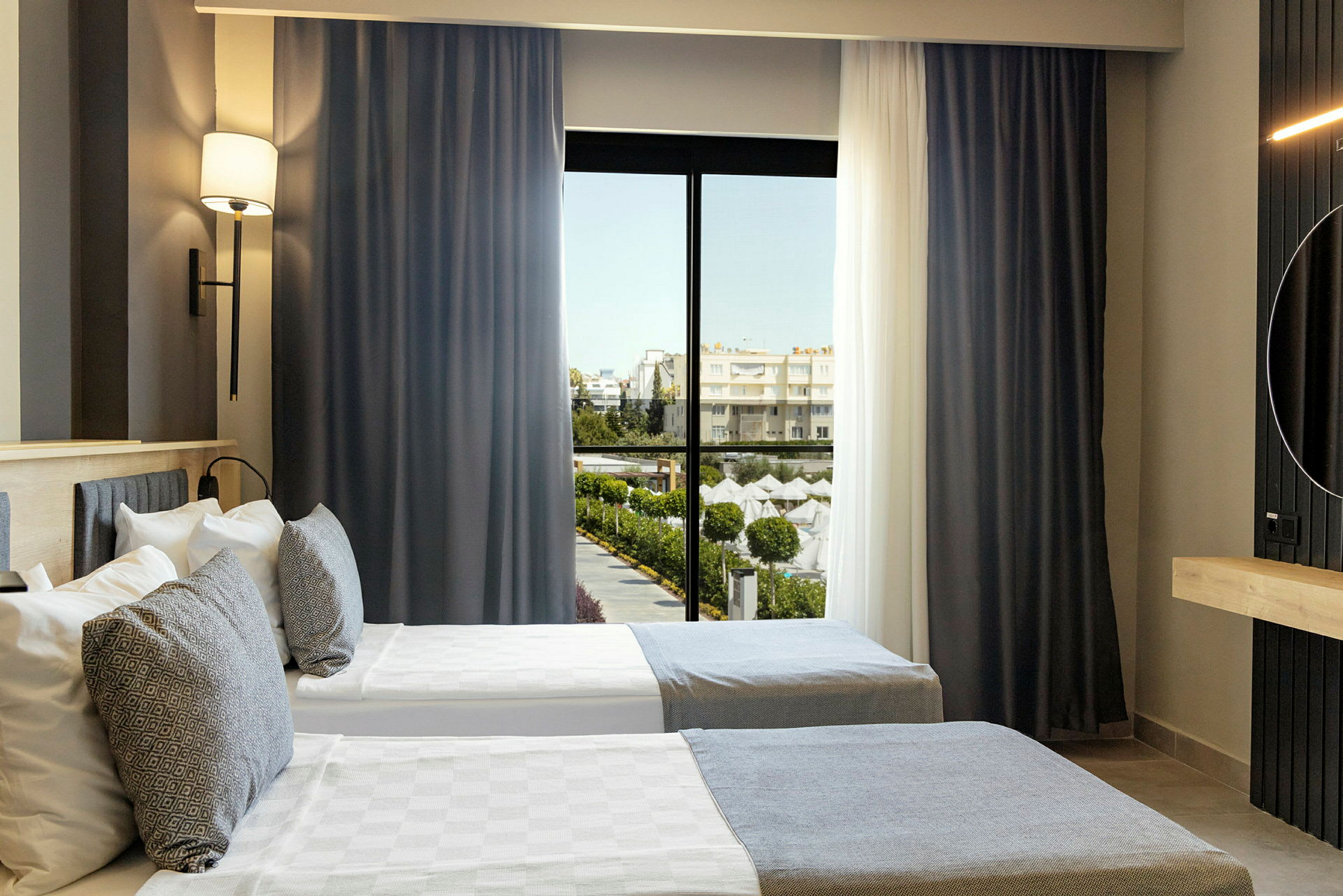 Hotellrom med to enkeltsenger og vindu med utsikt mot et bassengområde. (AI-generert tekst)
