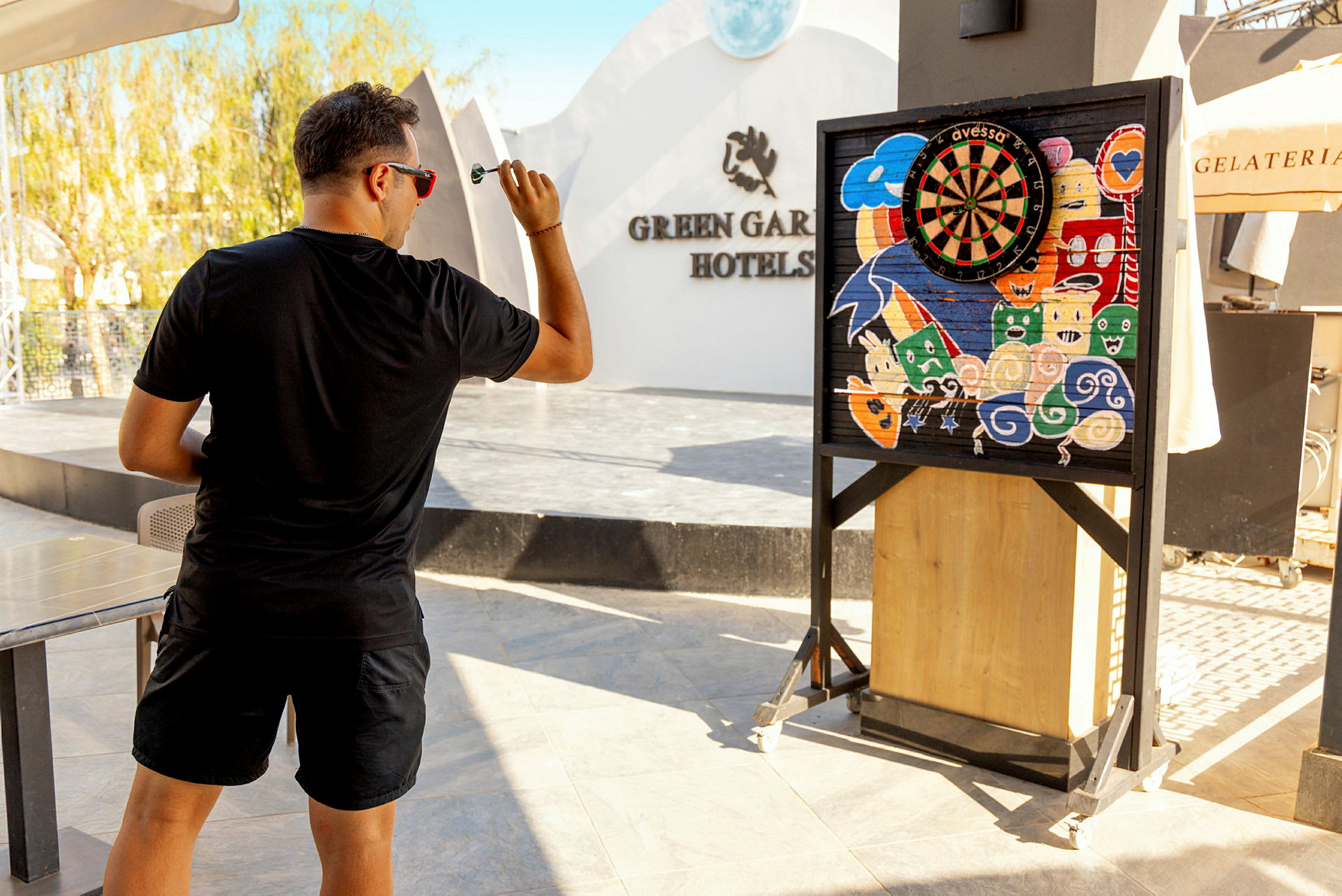 Mann spiller dart foran en fargerik darttavle på hotellet. (AI-generert tekst)