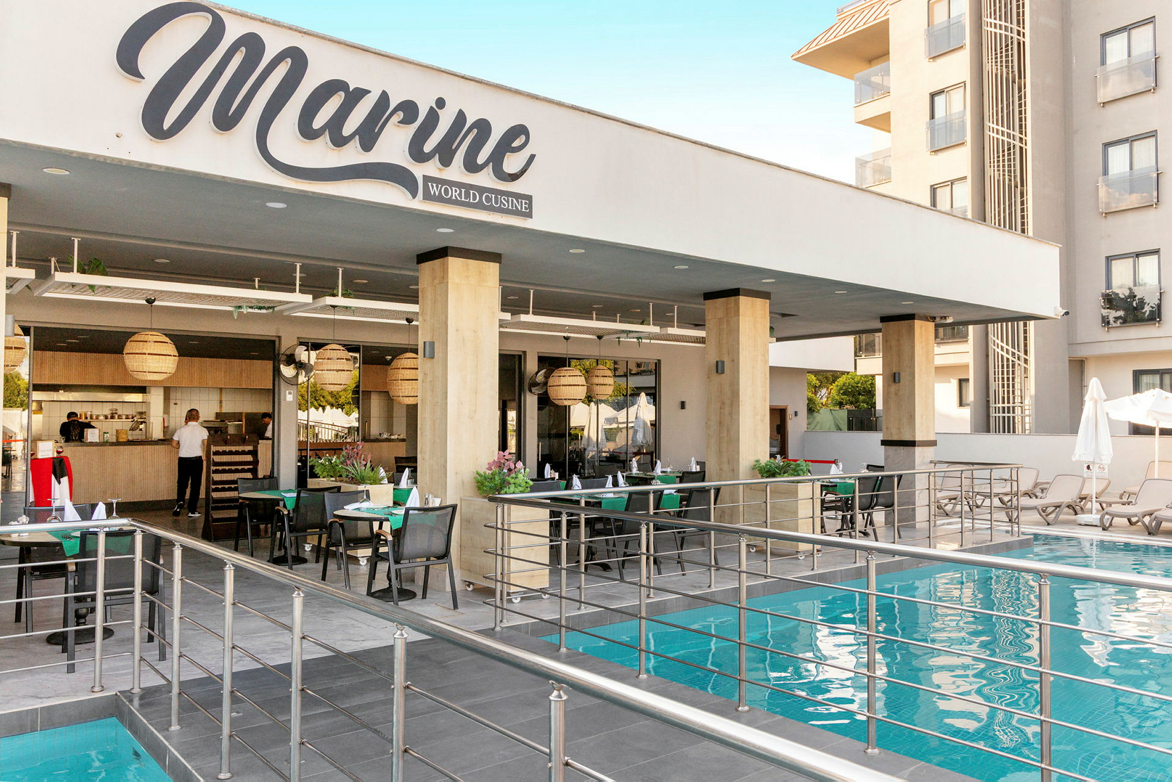 En restaurant ved navn Marine World Cuisine plassert ved siden av et basseng med sitteplasser og bord. (AI-generert tekst)