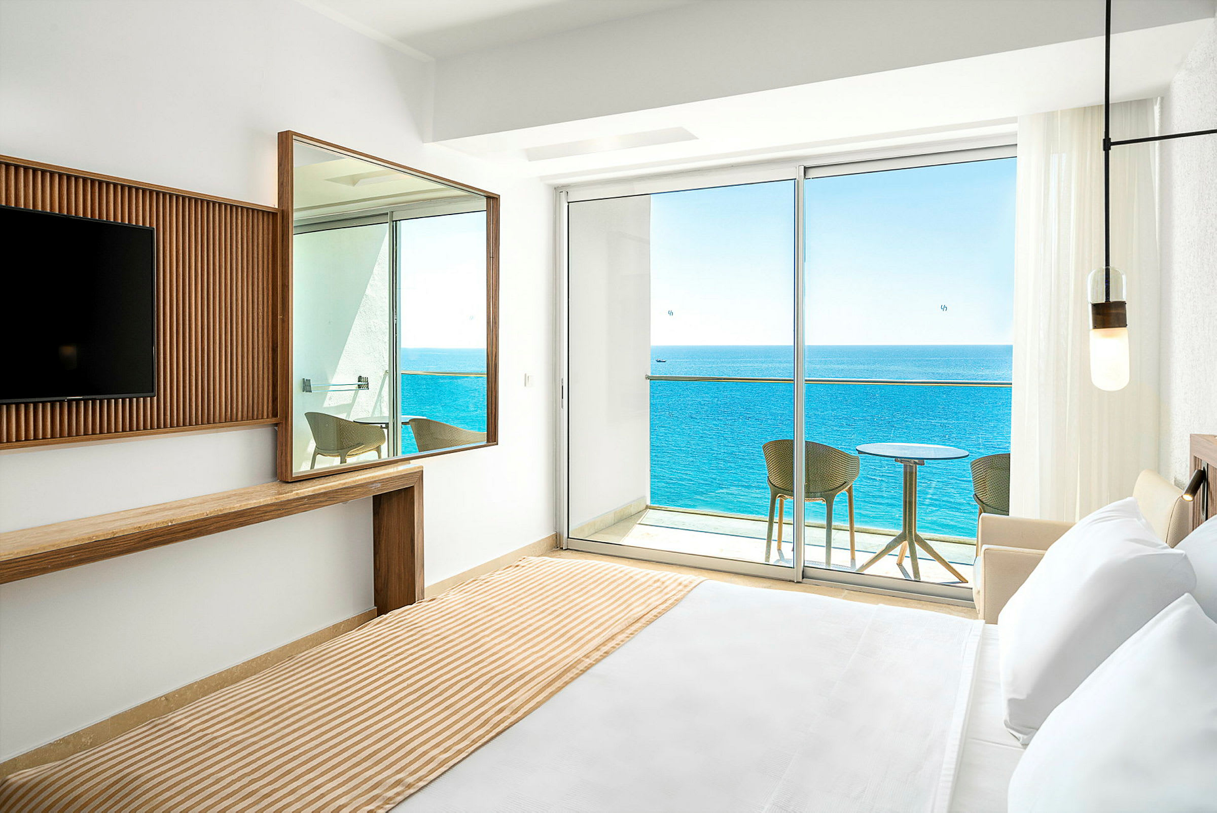 Hotellrom med utsikt over havet fra balkong. (AI-generert tekst)