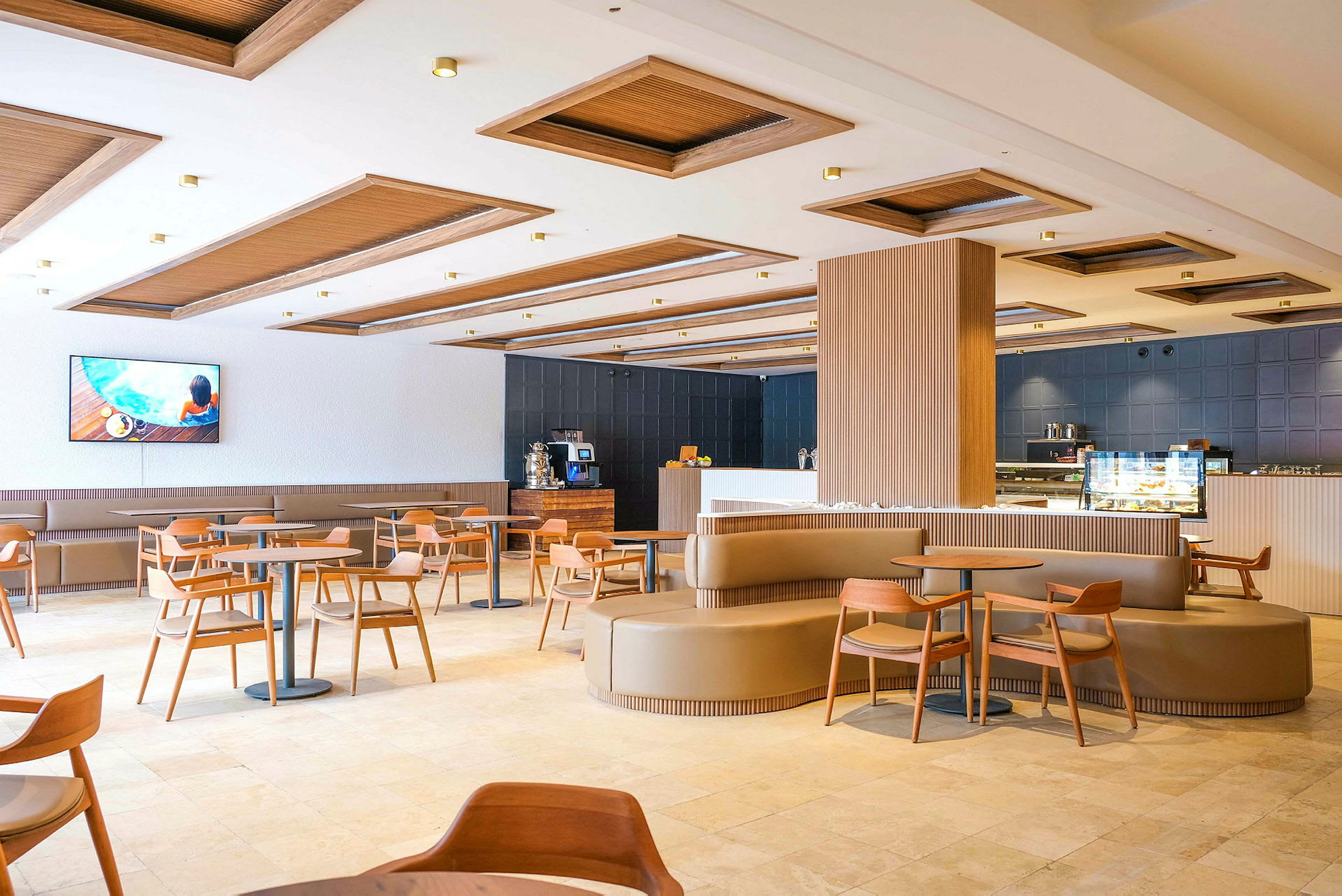 En moderne restaurant med tretak, bord og stoler samt en bar og en TV på veggen. (AI-generert tekst)