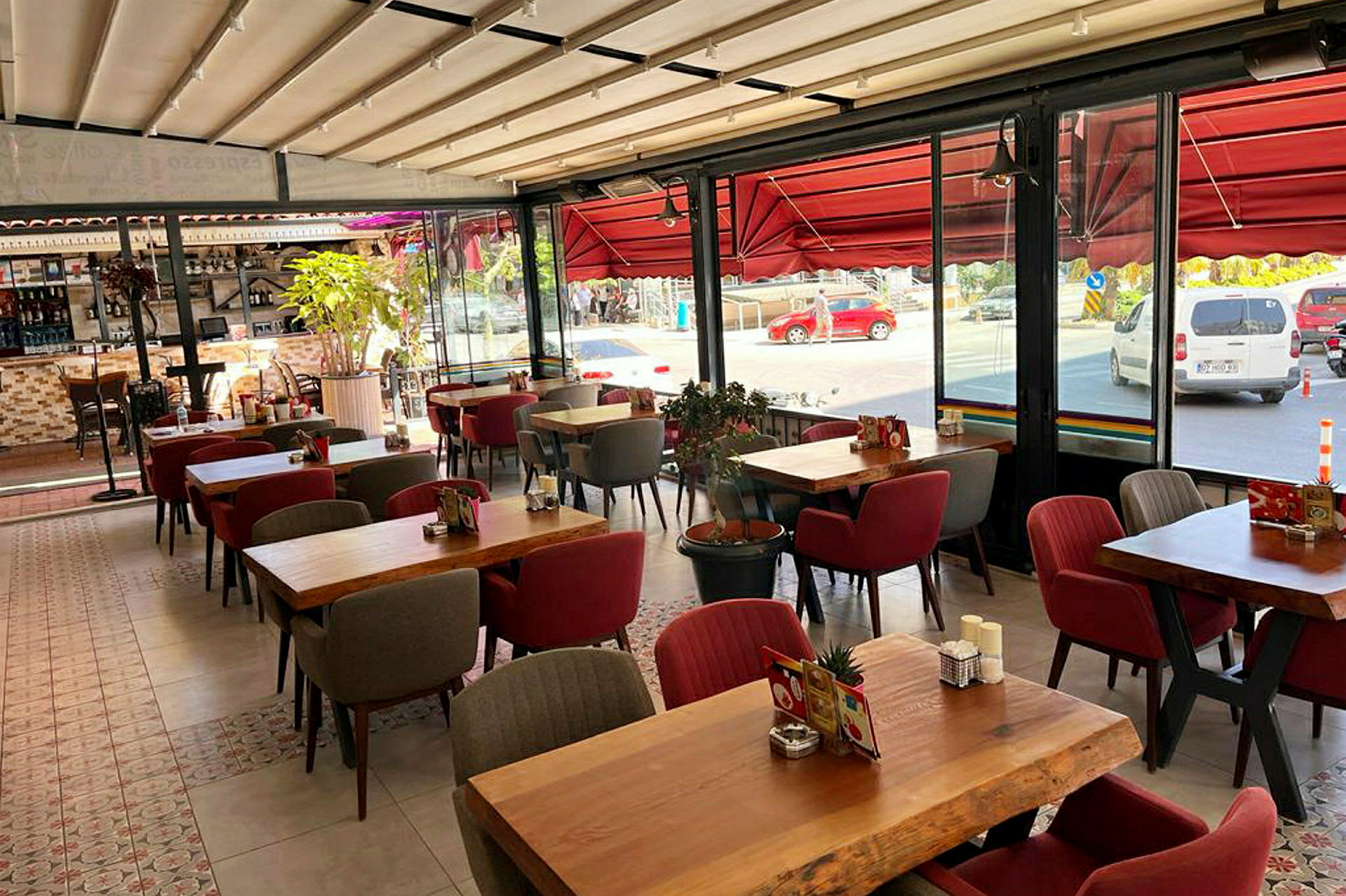 En restaurant med bord og stoler og store vinduer mot gaten. (AI-generert tekst)