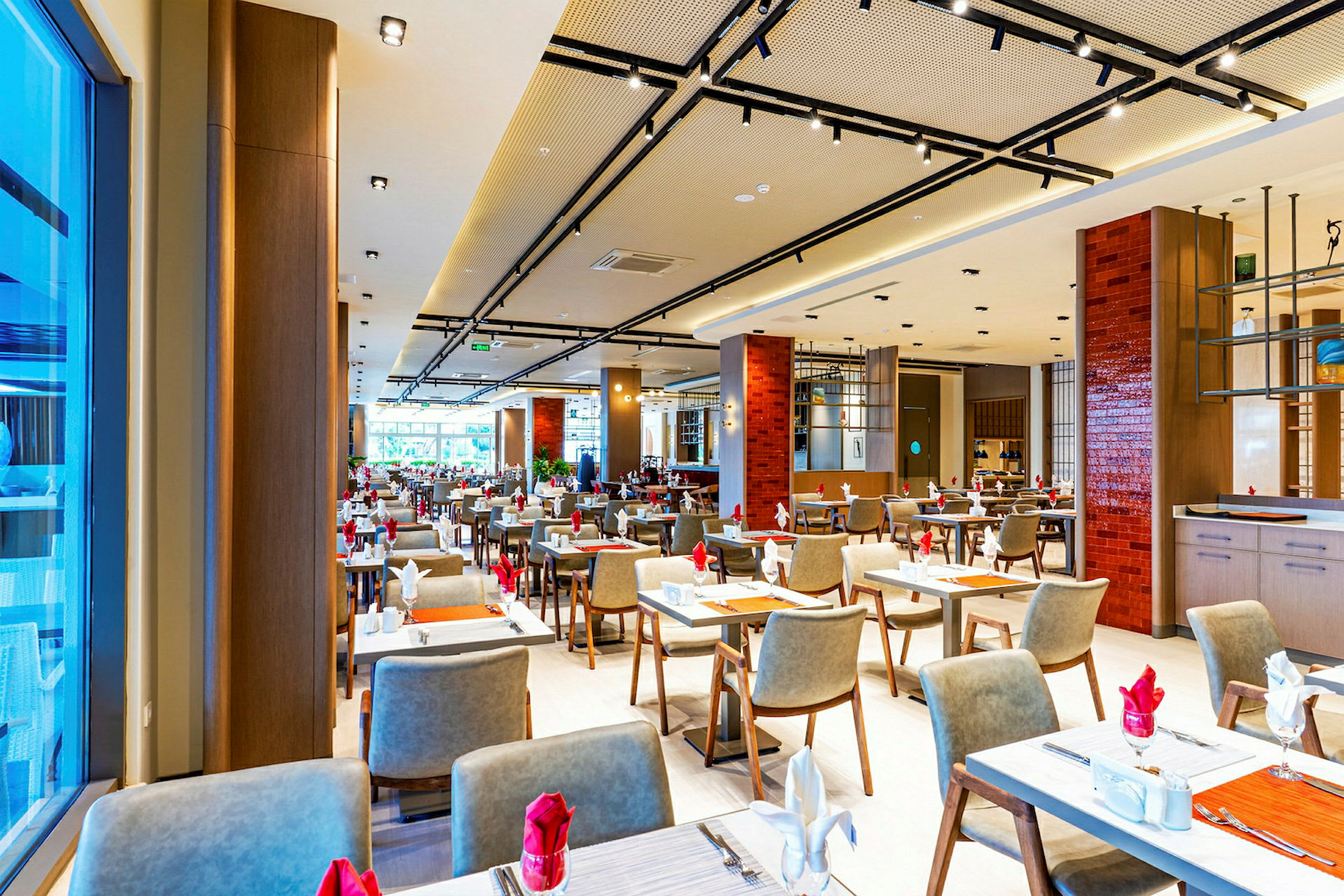 Bilde av en elegant restaurant med mange dekkede bord og moderne møbler. (AI-generert tekst)