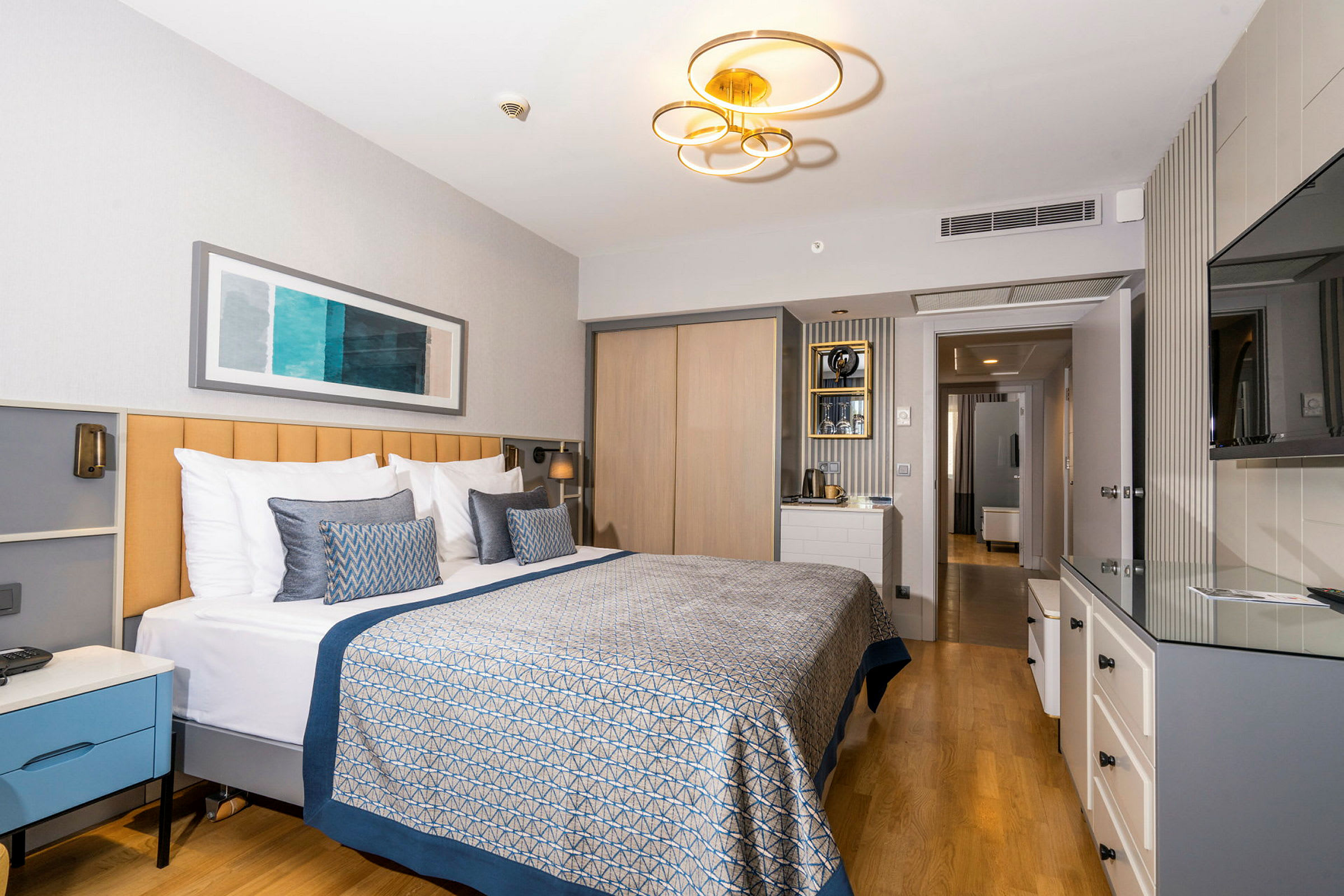Moderne hotellrom med en stor dobbeltseng, lys innredning og et tregulv. (AI-generert tekst)