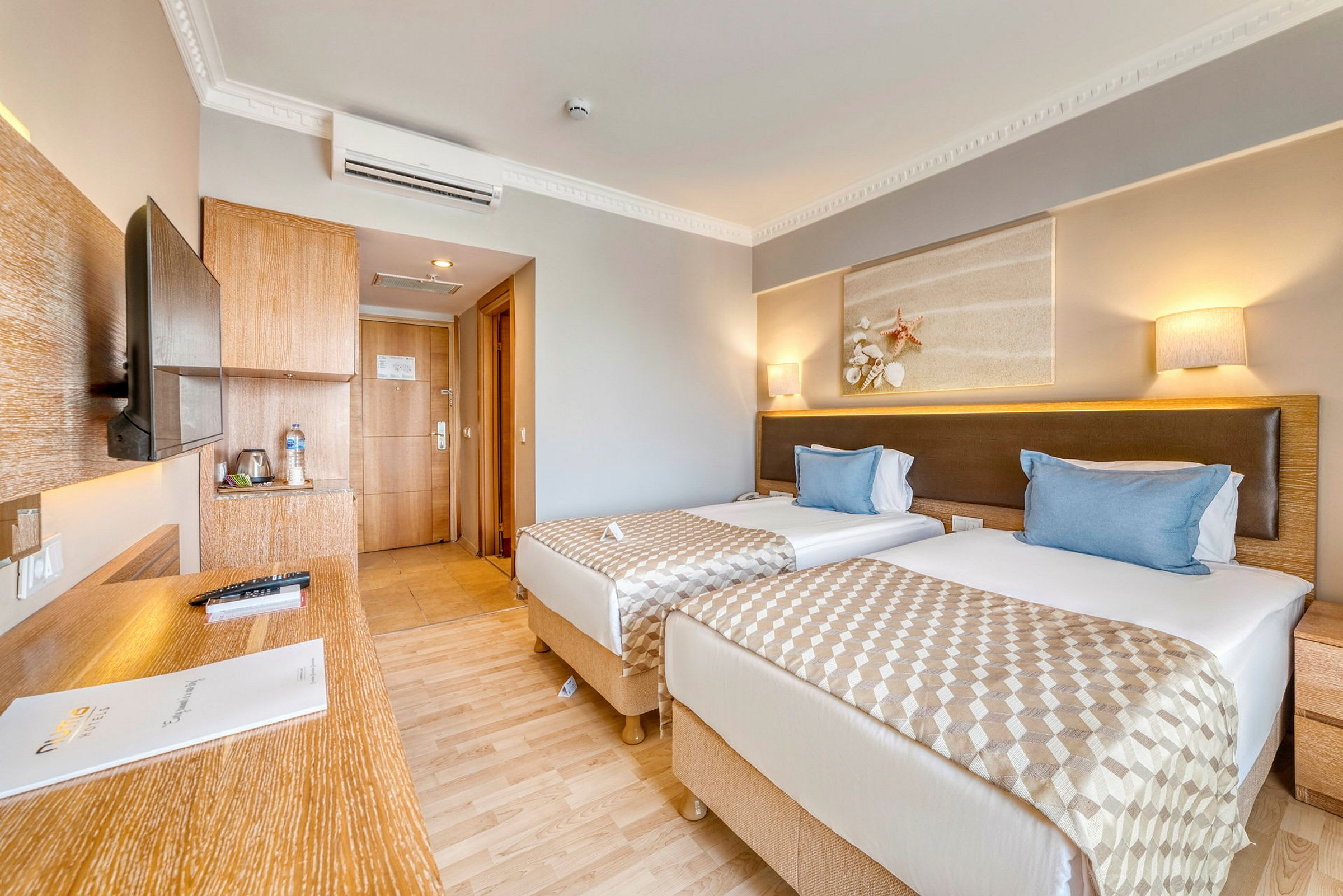 Hotellrom med to enkelsenger, et skrivebord og en dør til badet. (AI-generert tekst)