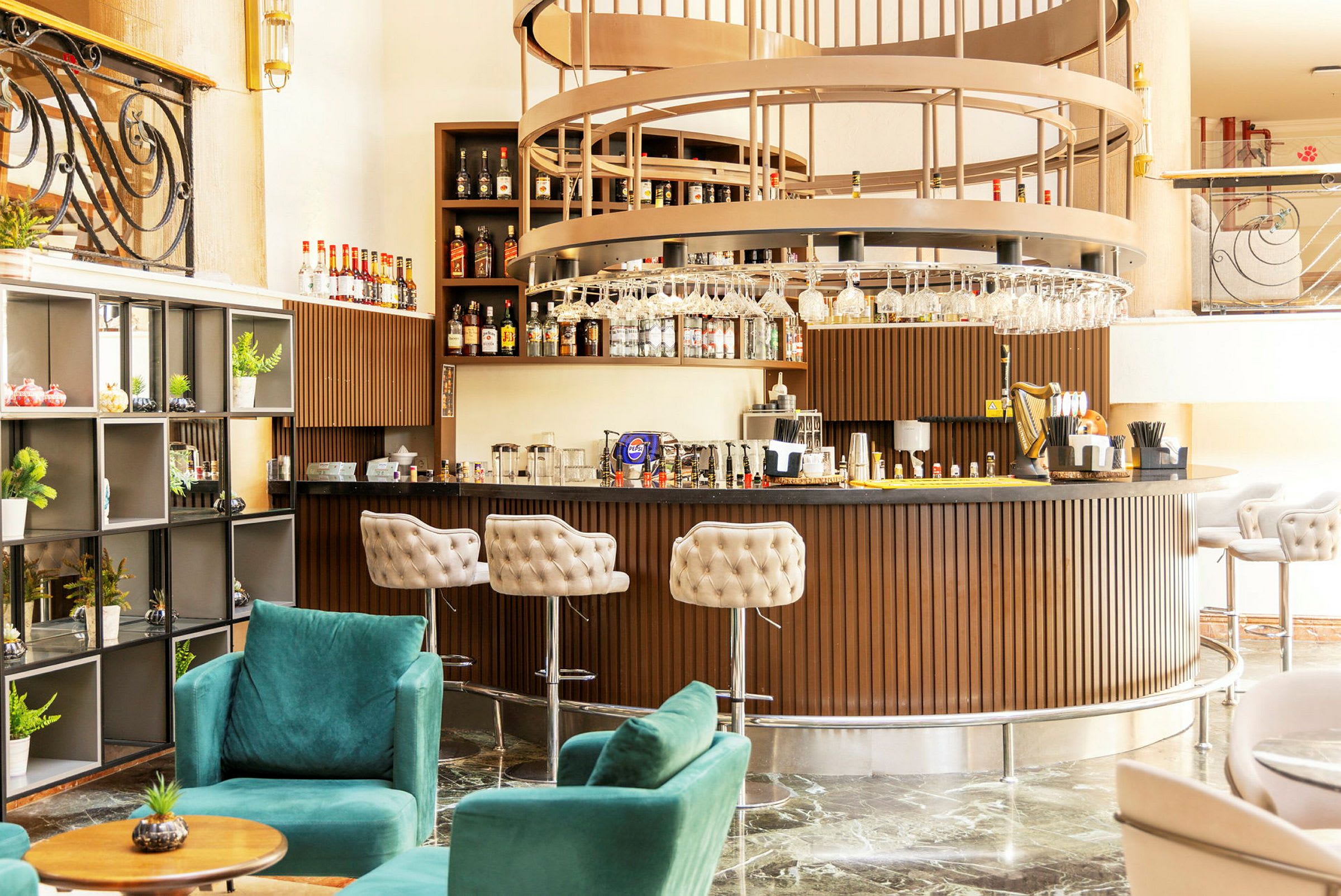 En stilig hotellbar med elegant innredning, inkludert grønne lenestoler og en rund bardisk i tredesign. (AI-generert tekst)
