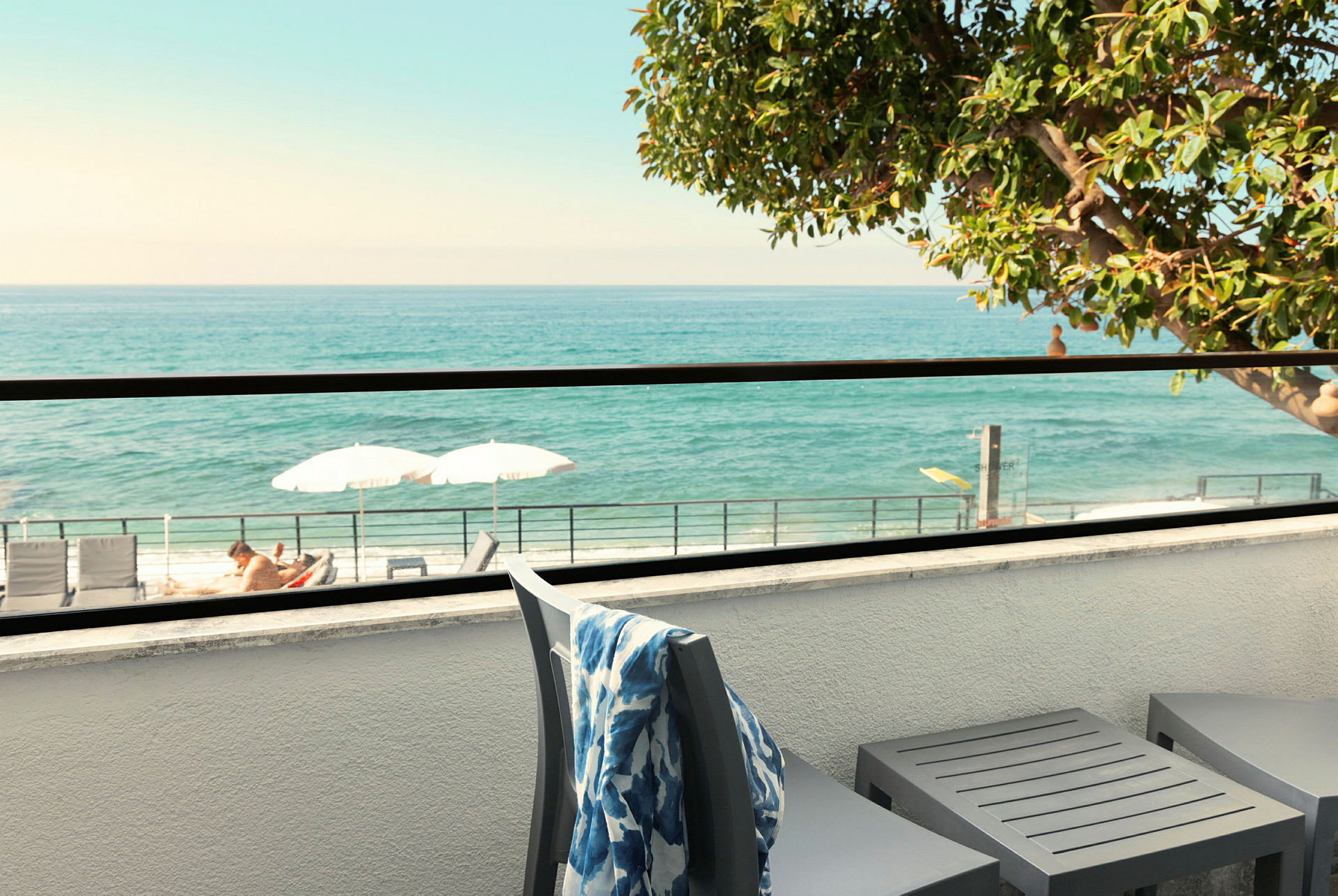 Terrasse med utsikt over havet, solsenger og parasoller synlige. (AI-generert tekst)