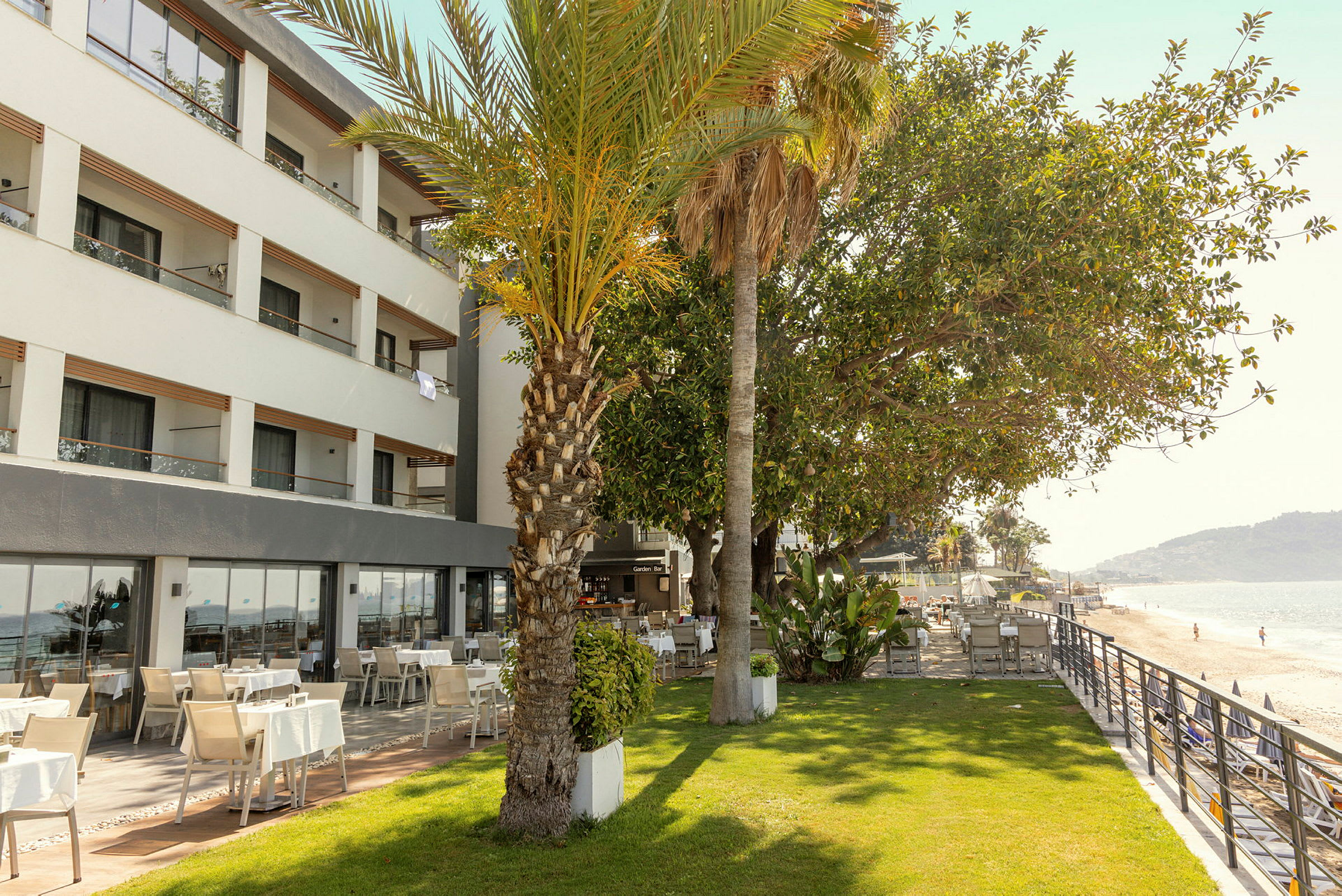 Hotell med utendørs utsikt over en grønn plen og en strand. (AI-generert tekst)