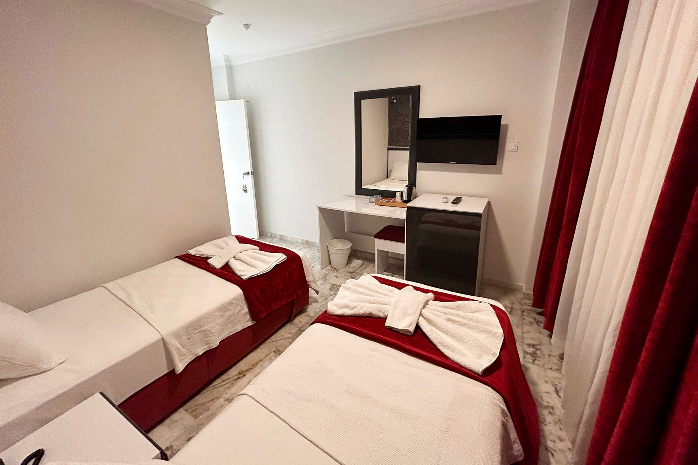 Hotellrom med to enkeltsenger, skrivebord og TV. (AI-generert tekst)