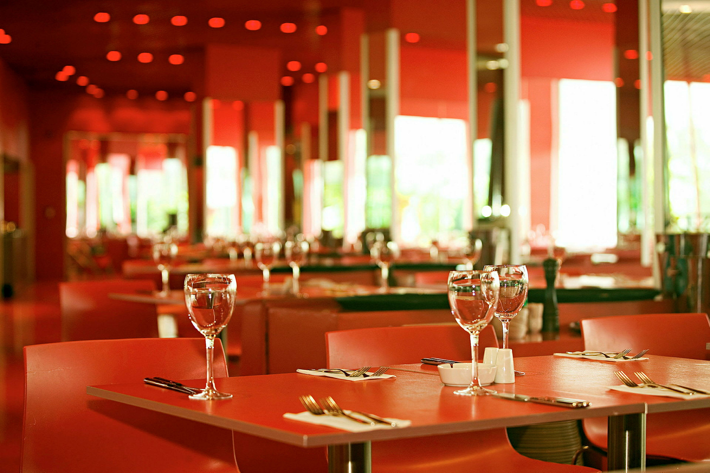 Et dekket bord i en elegant restaurant med rødt interiør. (AI-generert tekst)