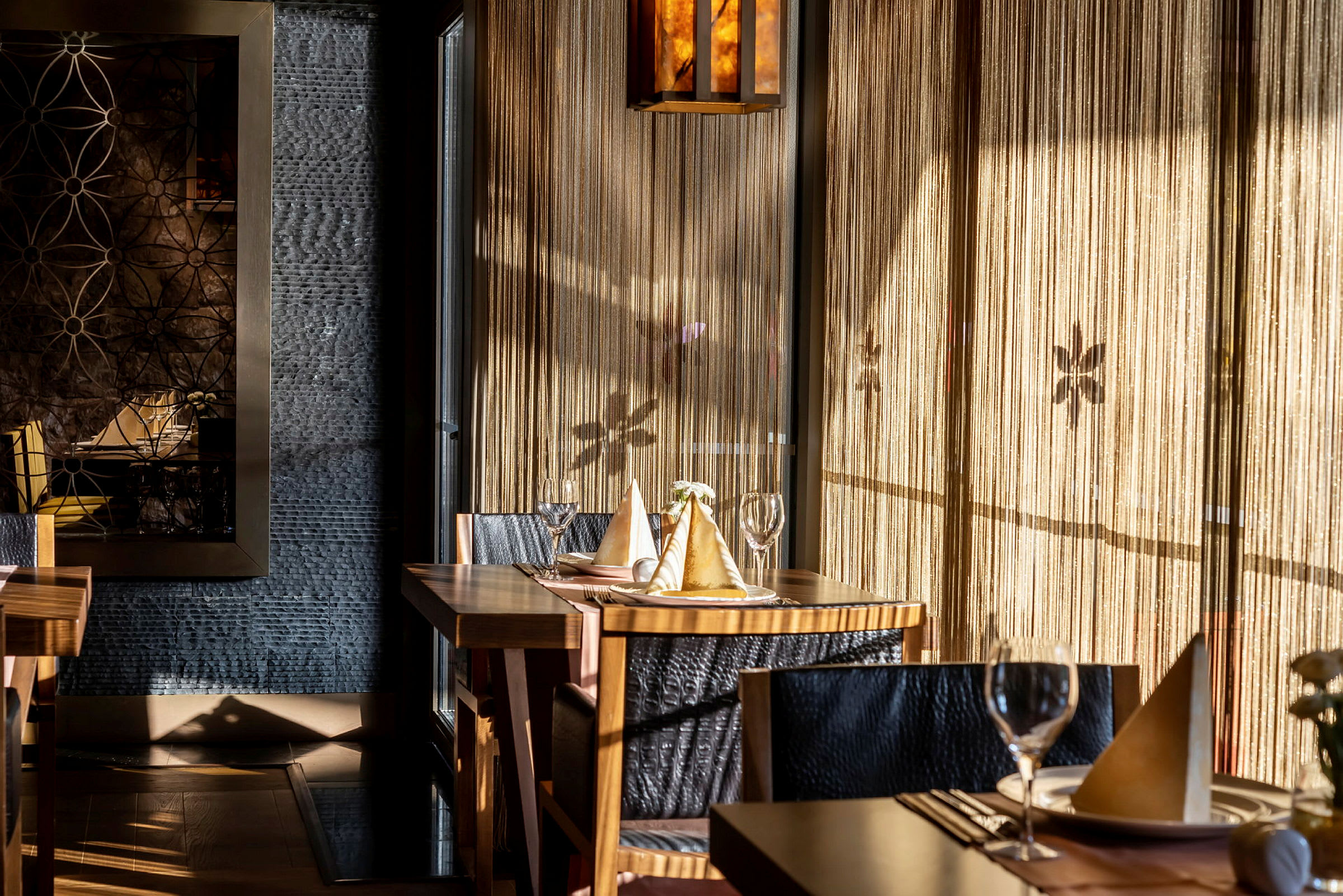 Interiør av en elegant restaurant med dekkede bord, lysinnslipp og dekorative veggelementer. (AI-generert tekst)