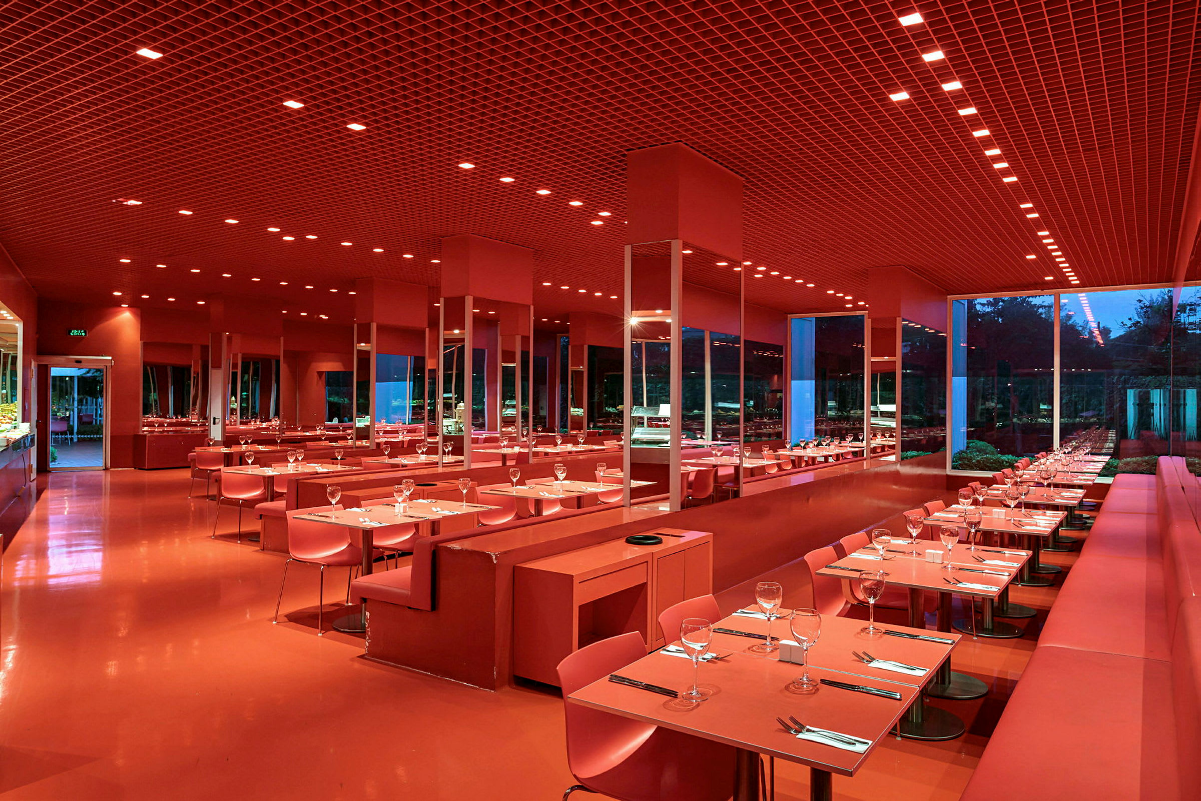En moderne restaurant med rød innredning, dekkede bord og store vinduer. (AI-generert tekst)