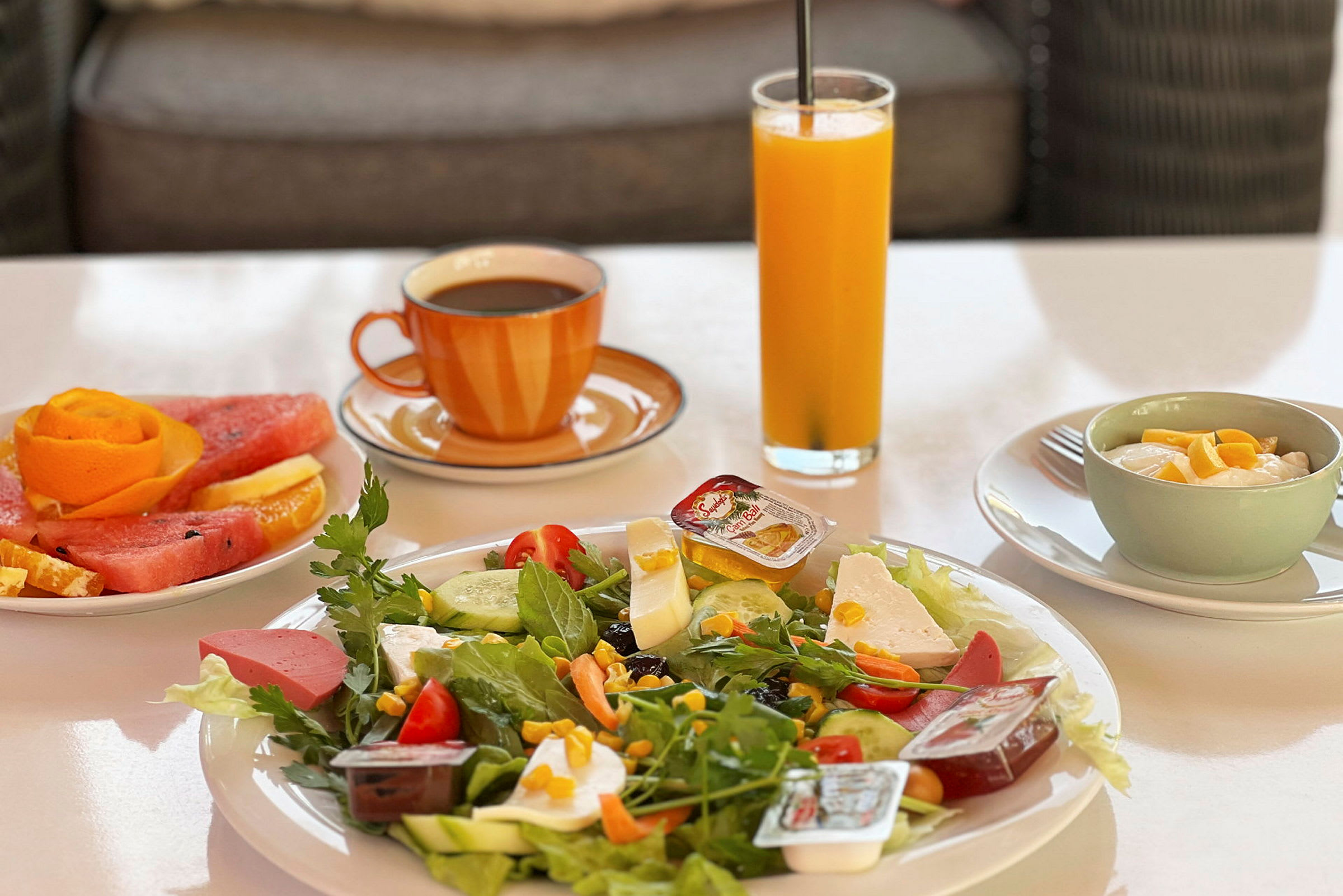 En frokost med salat, frukt, juice, kaffe og yoghurt. (AI-generert tekst)