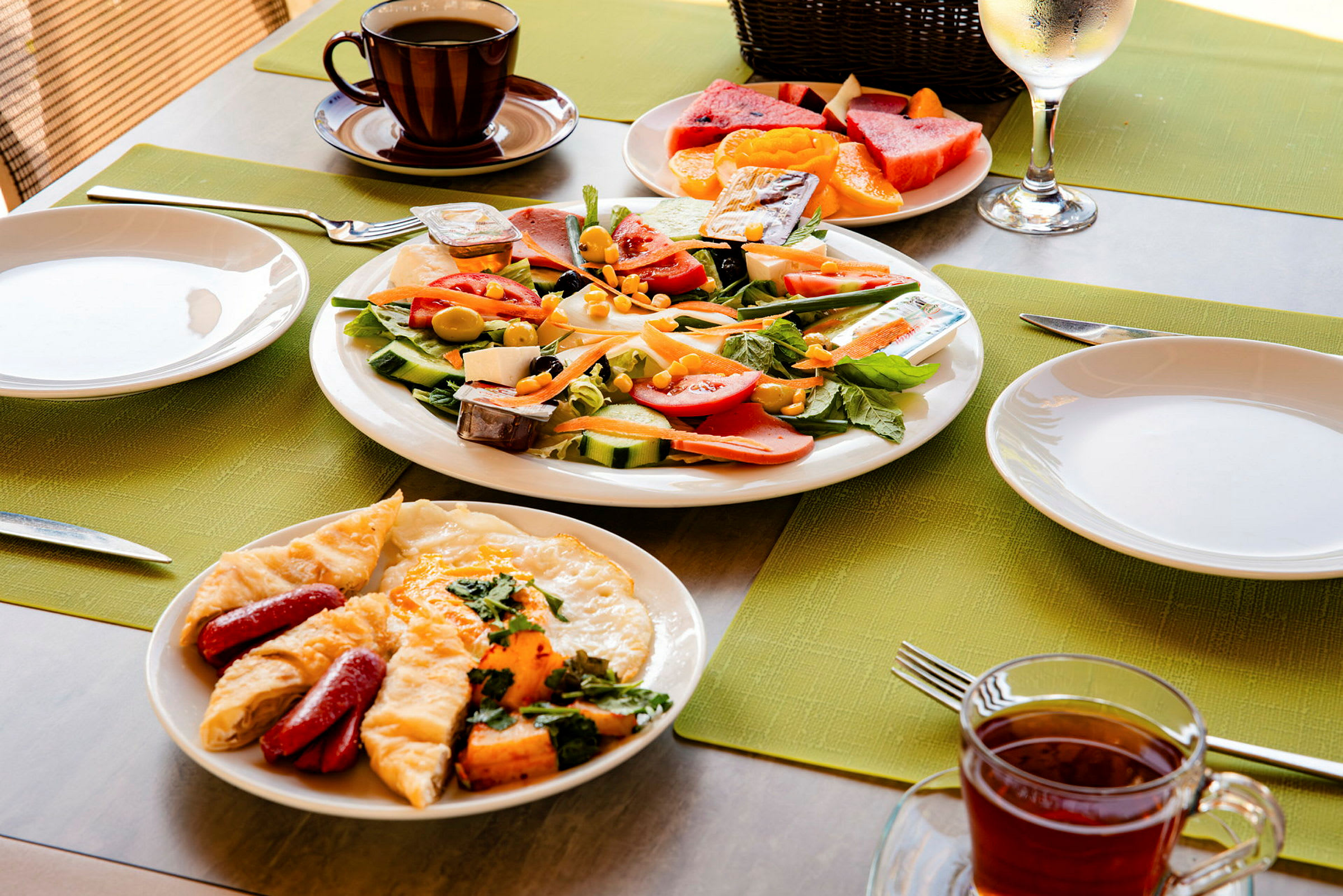 En frokostservering med salat, stekt egg med pølse og kaffe. (AI-generert tekst)