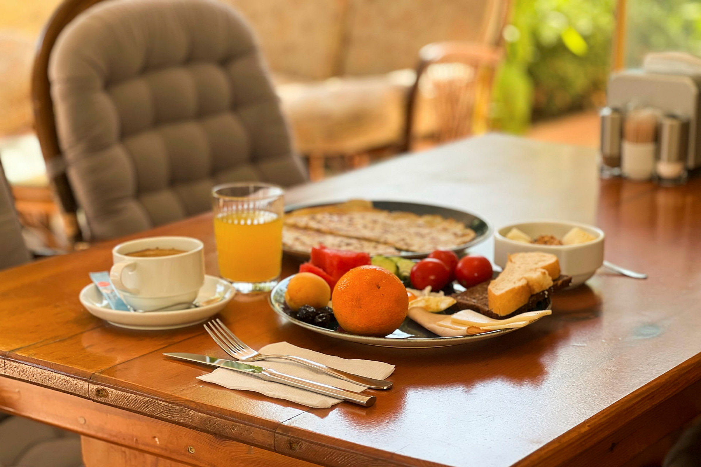 Frokost med appelsin, juice, brød og grønnsaker på bordet. (AI-generert tekst)