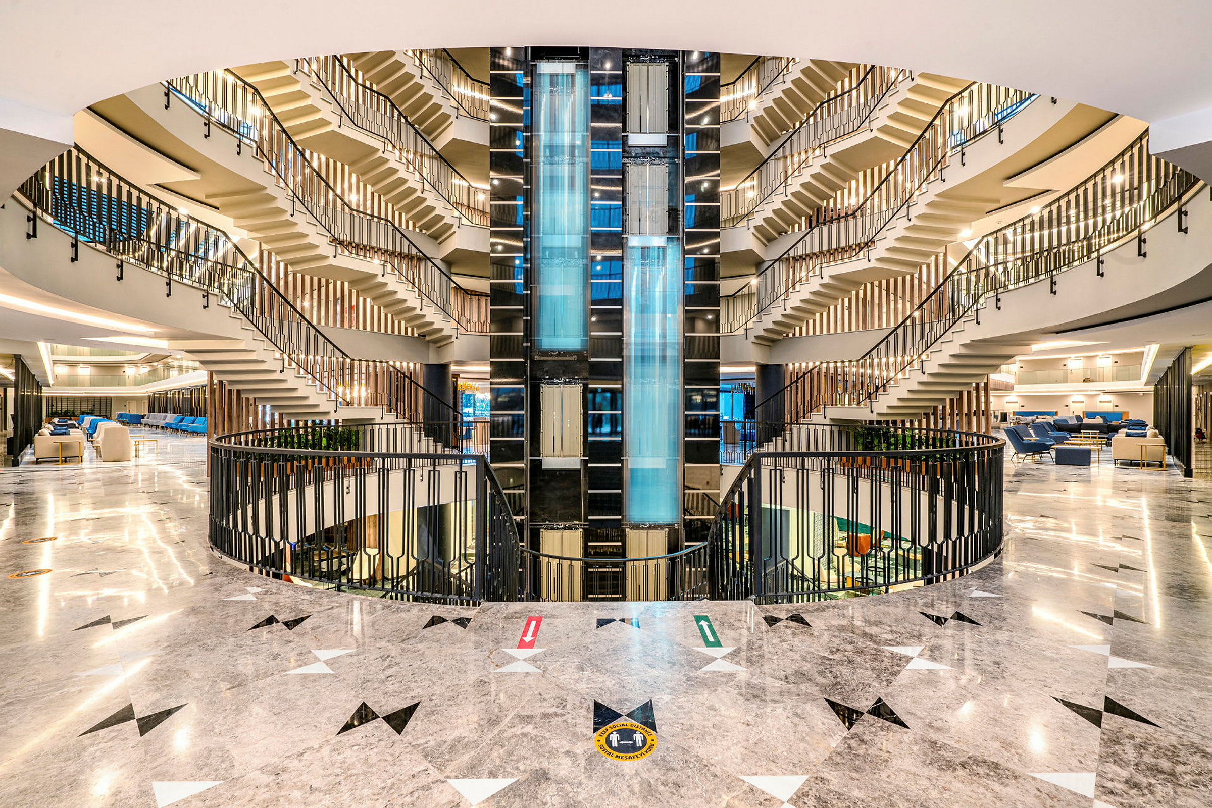 Hotellets atrium med lysdesign, glassheiser og trapper som fører oppover. (AI-generert tekst)