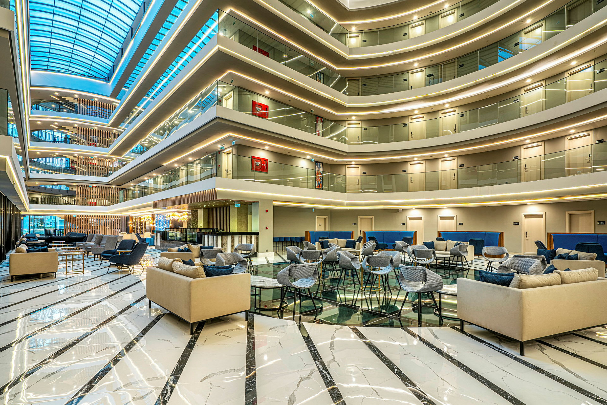 Moderne salongmøbler i en romslig hotellobby med glasstak. (AI-generert tekst)