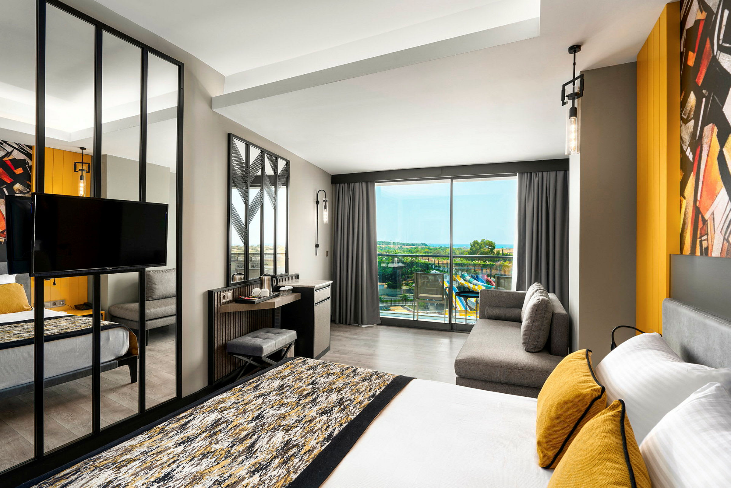 Moderne hotellrom med seng, sofa og utsikt mot balkong med panoramautsikt. (AI-generert tekst)