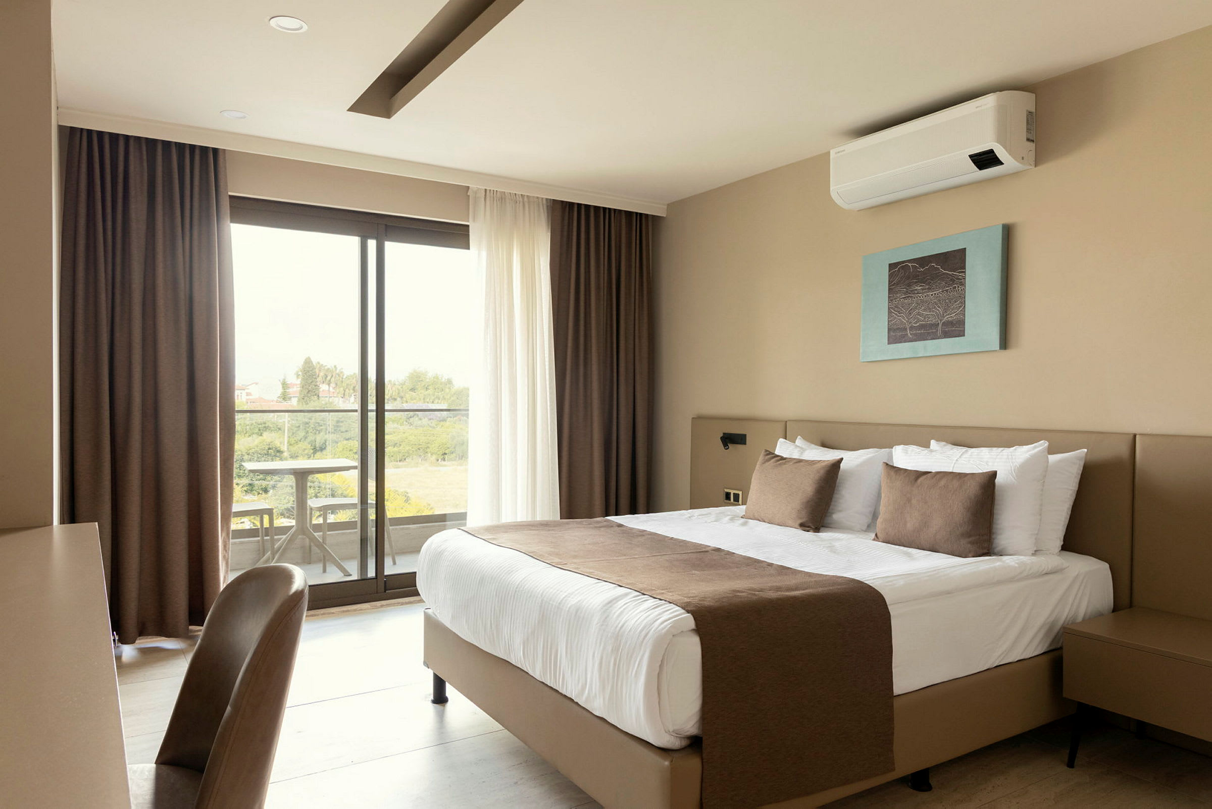Et hotellrom med en dobbeltseng, et bilde på veggen, et skrivebord med stol og et vindu som fører til en balkong med utsikt. (AI-generert tekst)