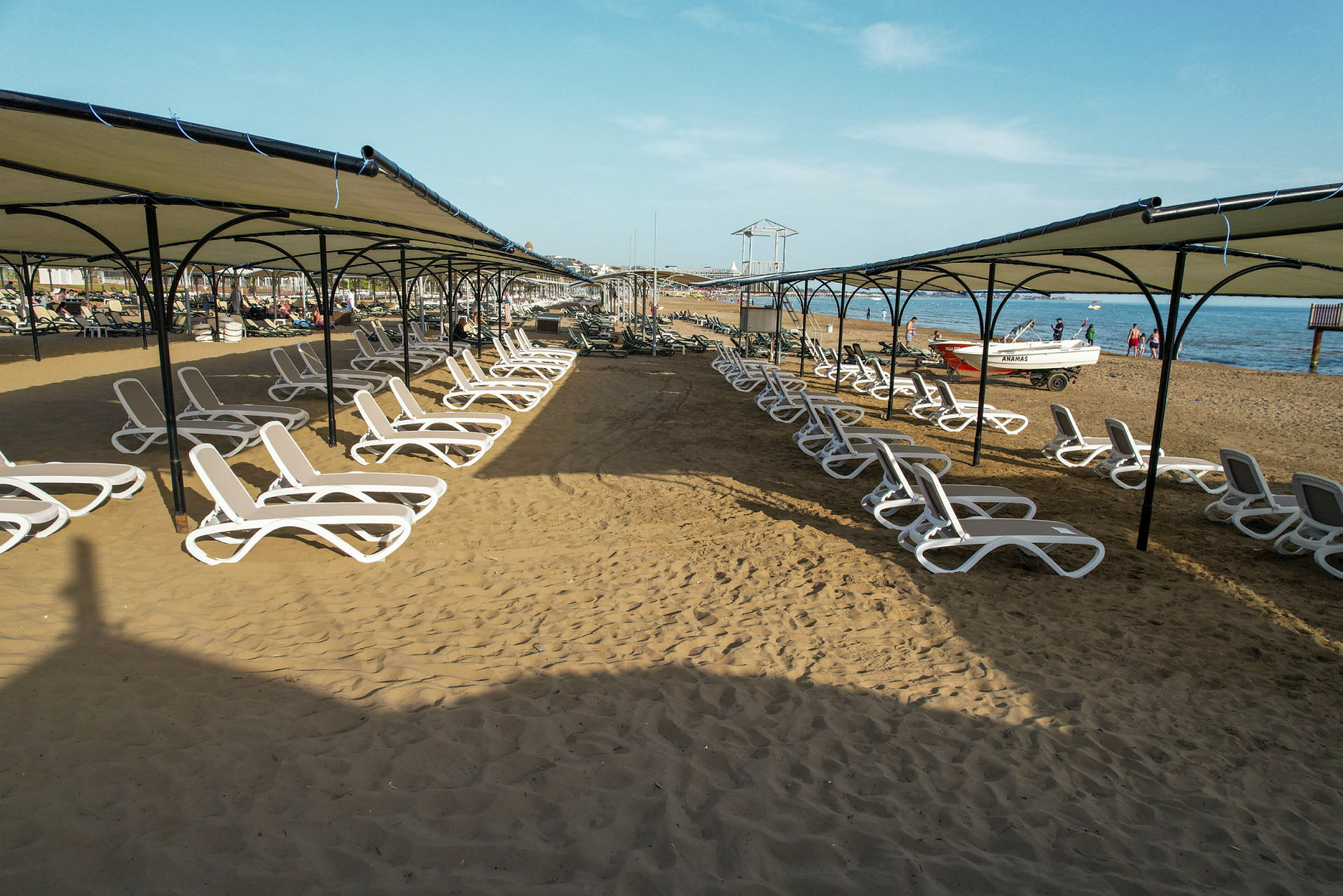 Solstoler under skyggefulle tak på en sandstrand ved havet. (AI-generert tekst)