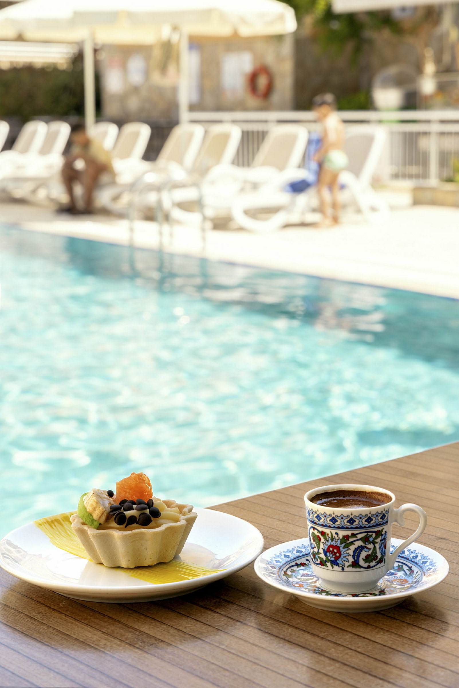 En kopp kaffe og en dessert ved kanten av et basseng. (AI-generert tekst)