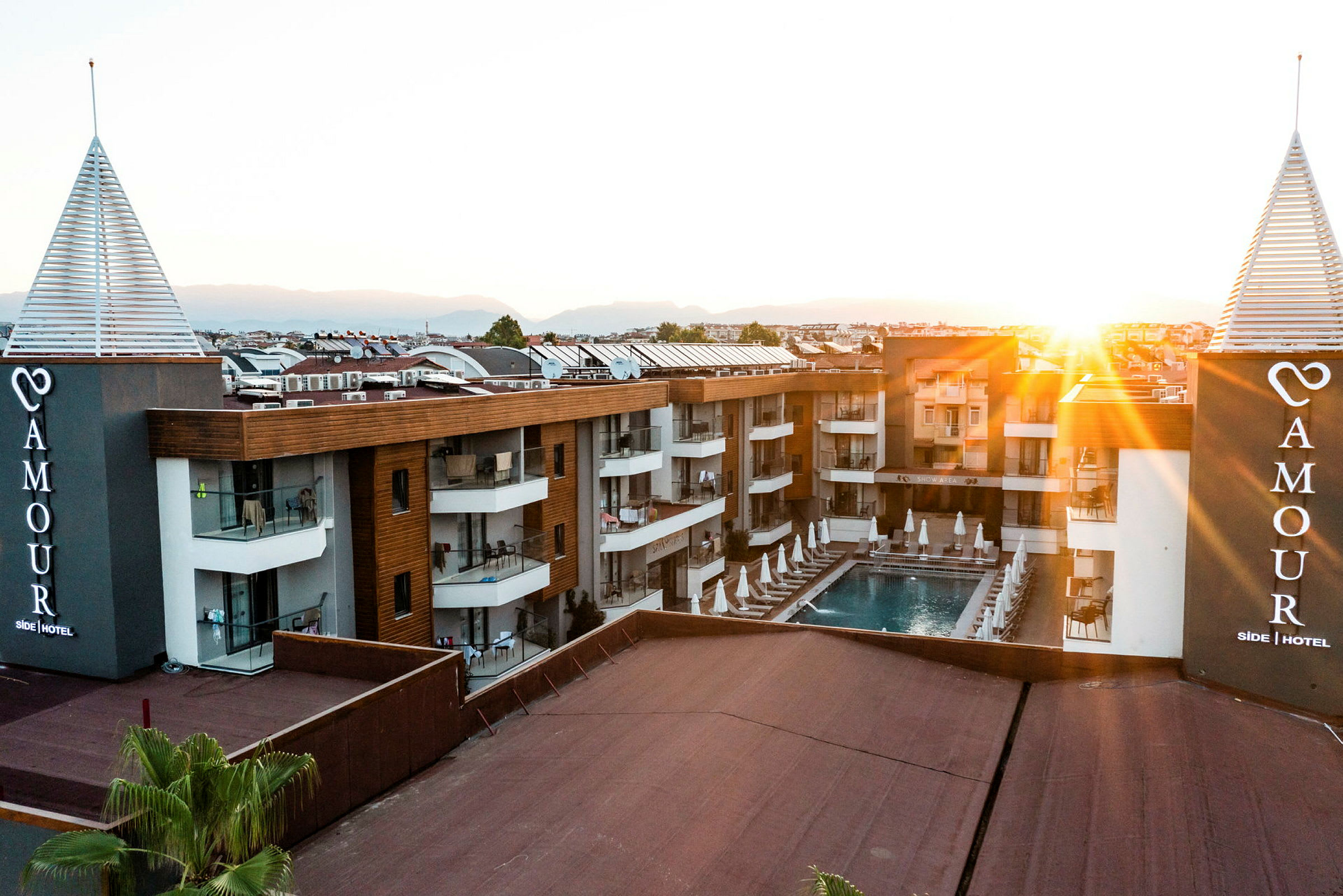 Hotellbygning med basseng og solsenger ved solnedgang. (AI-generert tekst)