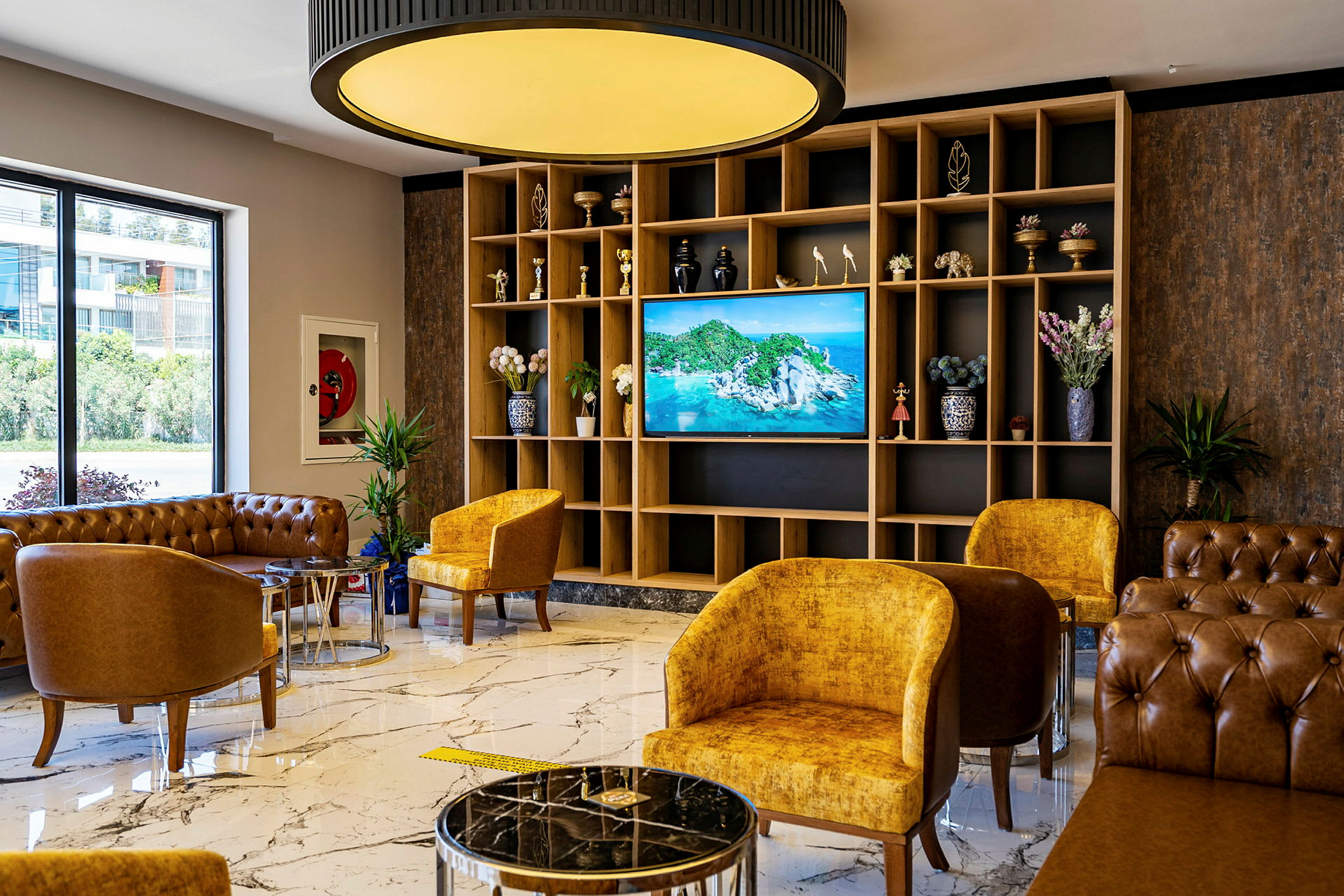 Hotellobby med sittemøbler, marmorgulv og en TV med naturutsikt. (AI-generert tekst)