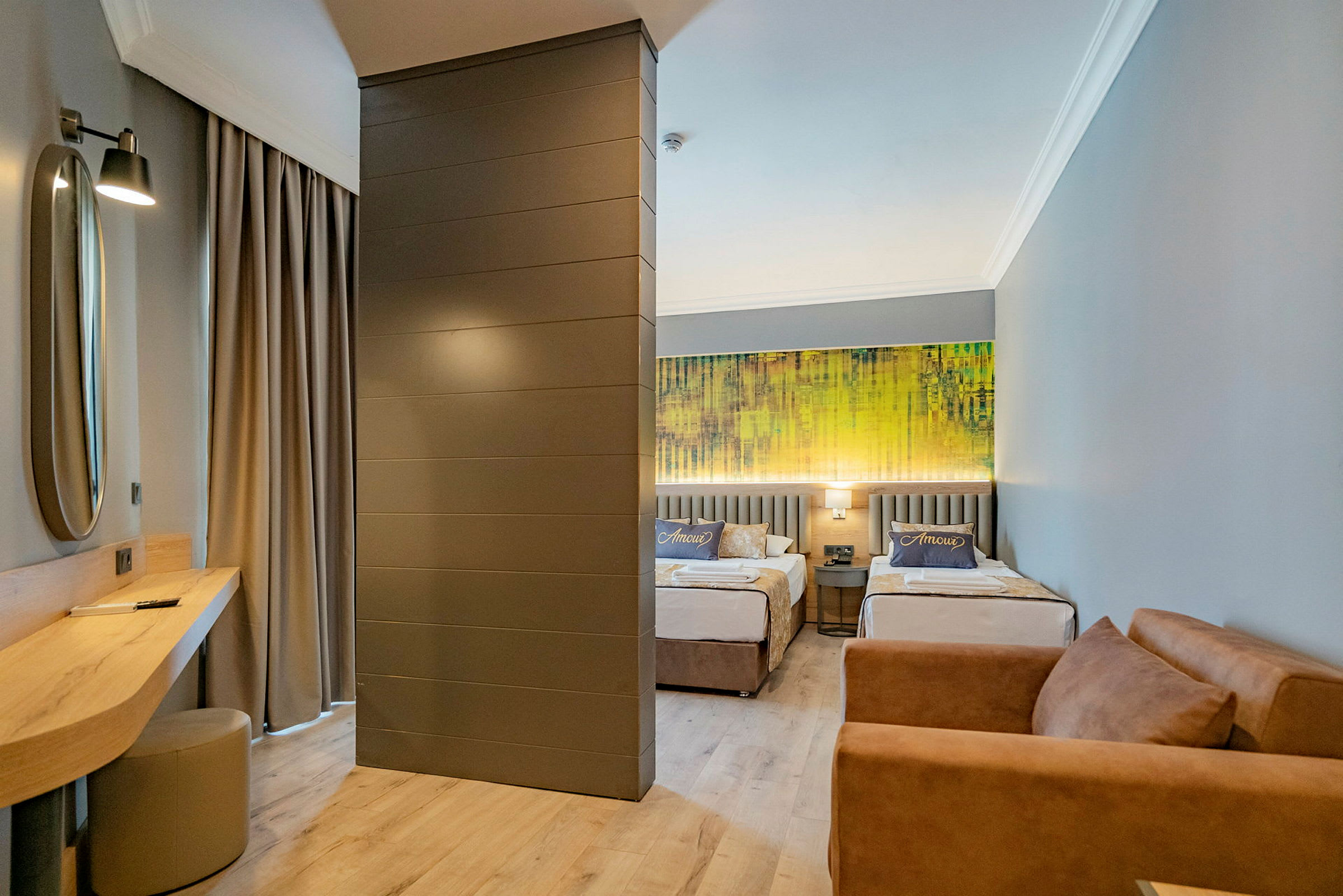 Hotellrom med to enkeltsenger, en sofa og et skrivebord. (AI-generert tekst)