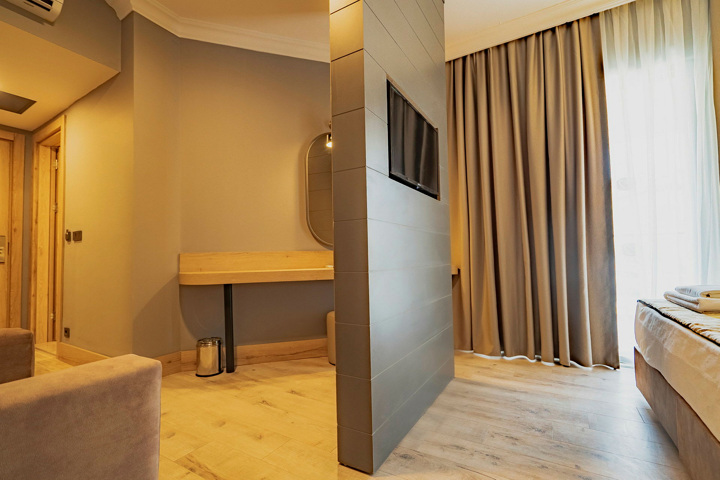 Moderne hotellrom med varm innredning, komfortable møbler og kombinert sitte- og soveområde. (AI-generert tekst)