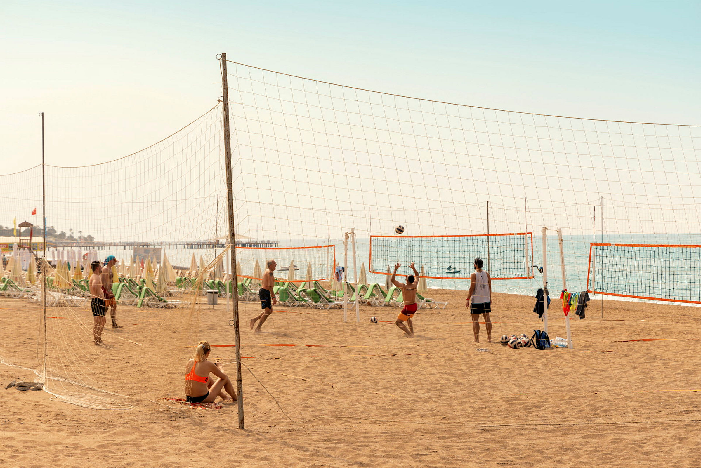 Personer spiller strandvolleyball på en sandstrand ved havet. (AI-generert tekst)