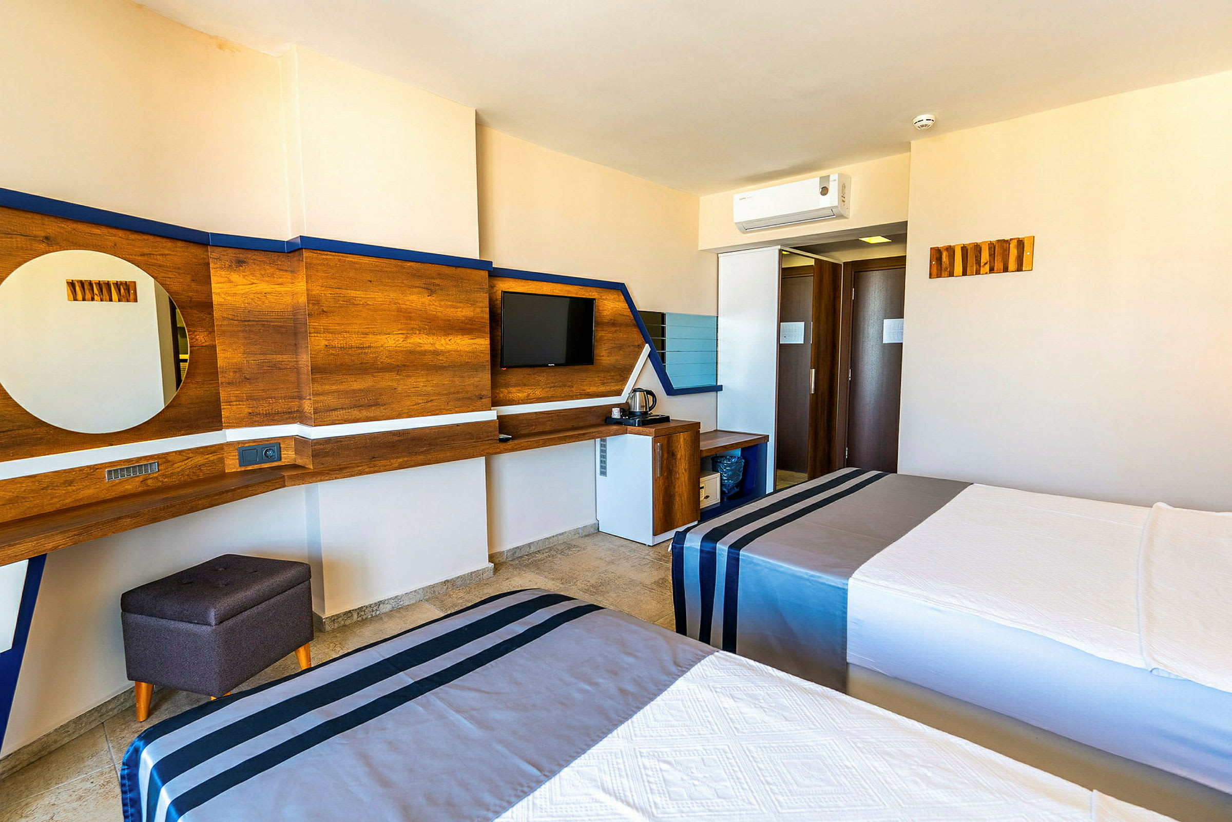 Hotellrom med to senger, TV på veggen og skrivebord med speil. (AI-generert tekst)