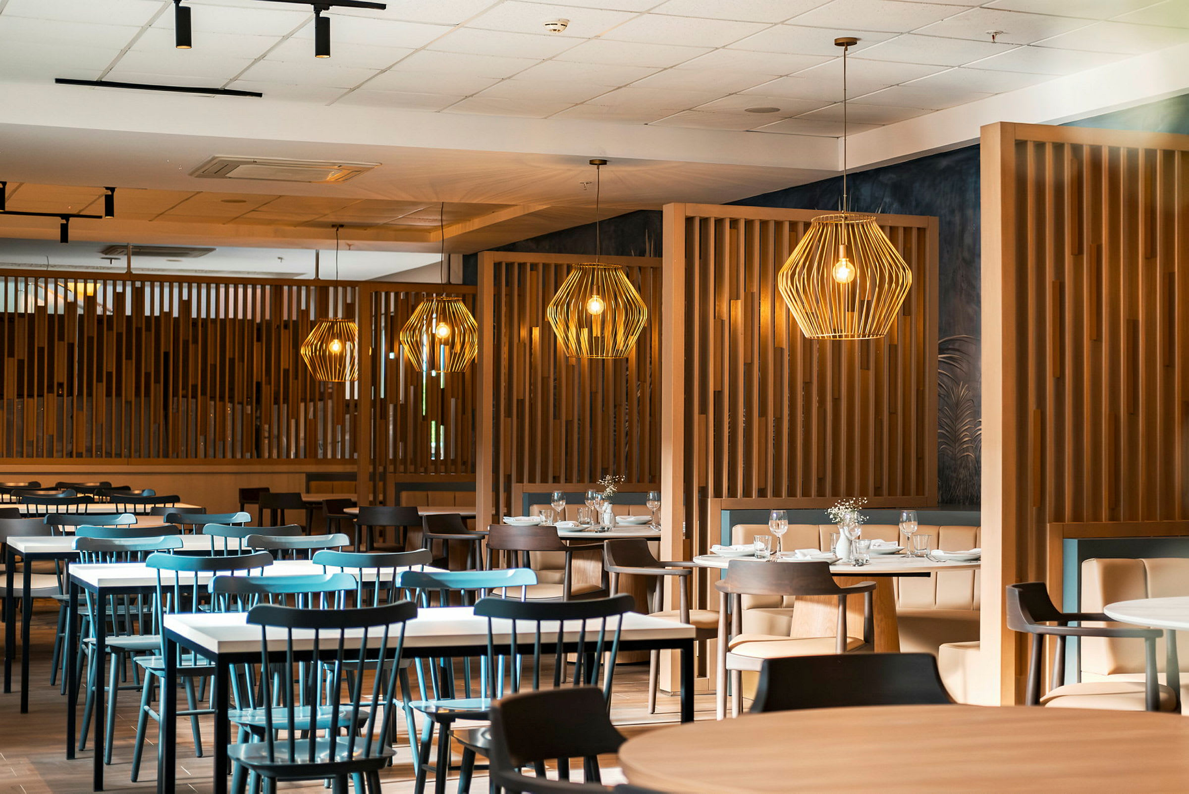 En restaurant med flere bord og stoler samt dekorative lamper. (AI-generert tekst)
