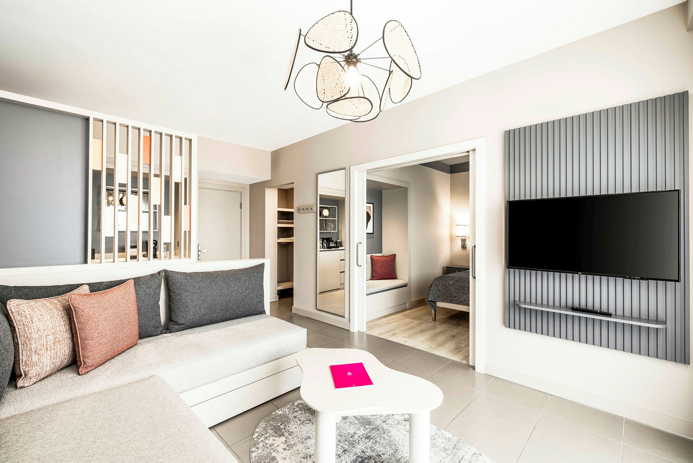 Et romslig og moderne innredet hotellrom med sittegruppe, soveplass og en veggmontert TV. (AI-generert tekst)