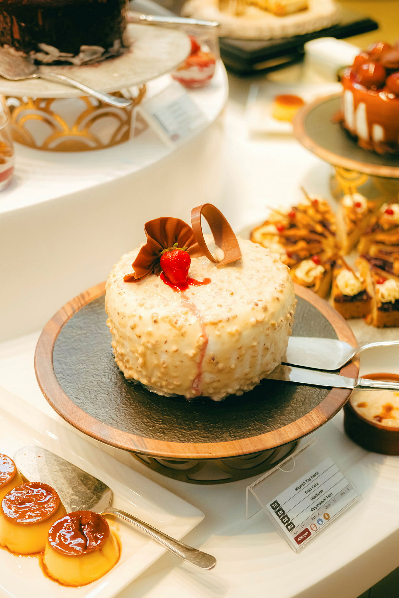 En dessertbuffé med forskjellige bakverk, inkludert en kremkake med sjokoladepynt og jordbær. (AI-generert tekst)