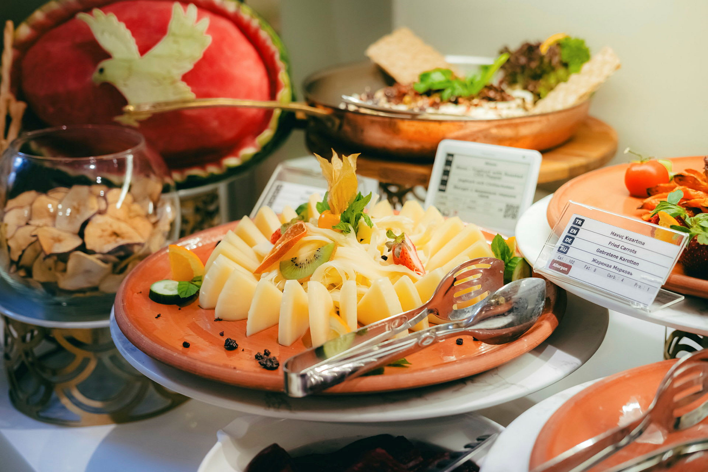 En buffet med ost dekorert med frukt og grønnsaker. (AI-generert tekst)