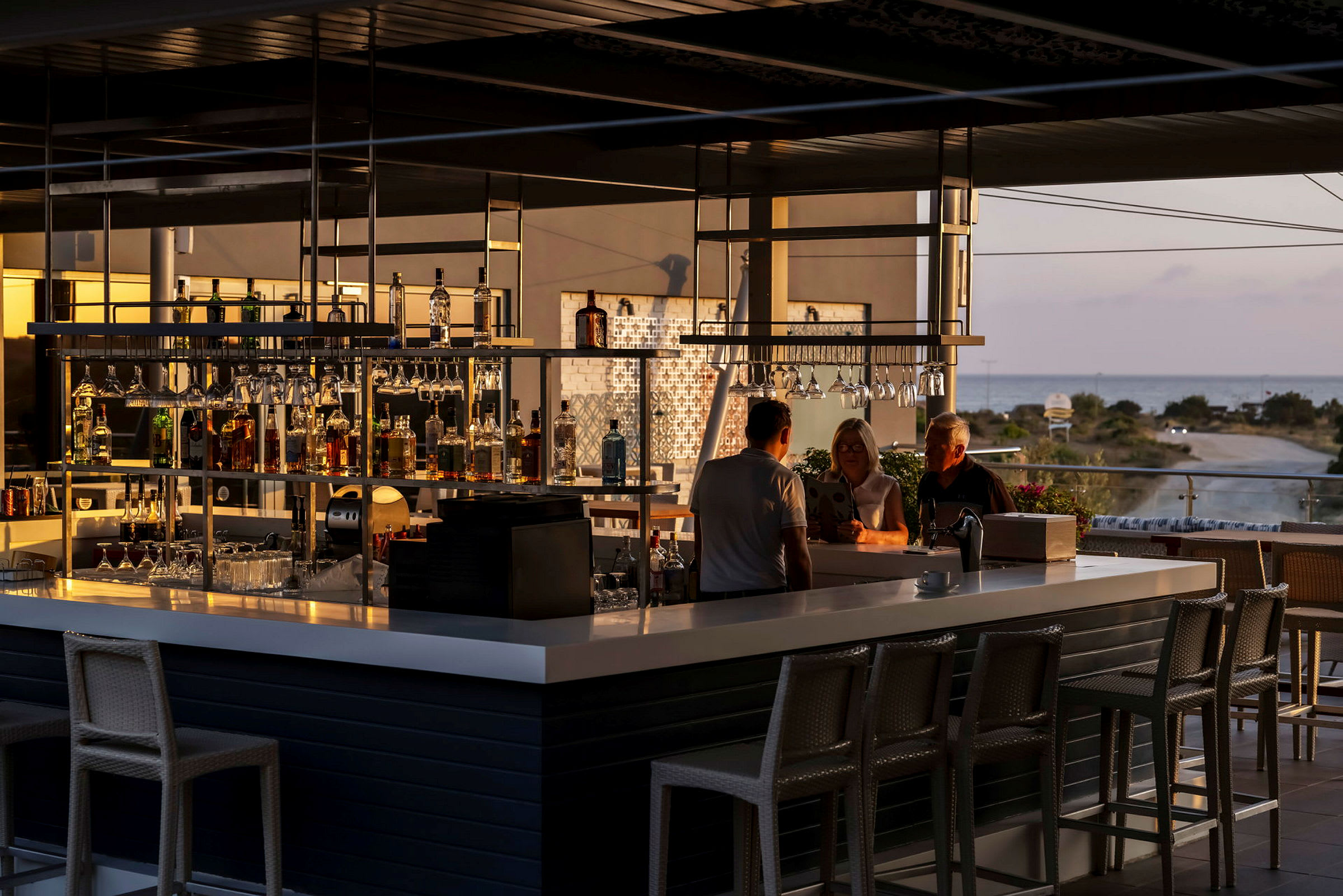 Utsikt over en moderne bar med sitteplasser og utsikt mot landskap og hav. (AI-generert tekst)